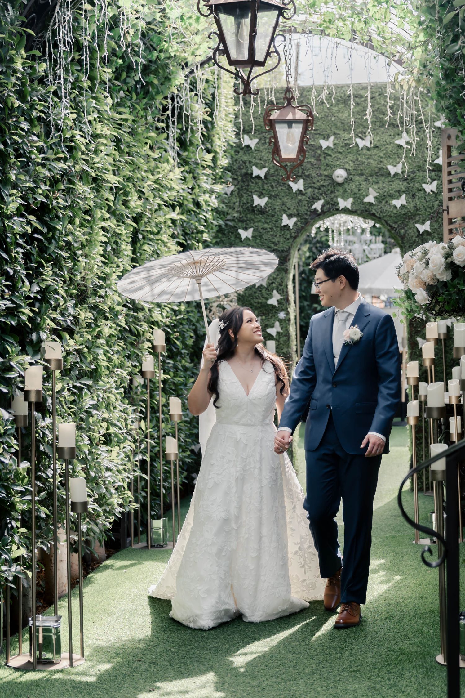 Couple shares romantic moments in a garden setting with hanging lanterns and lush greenery creating an enchanted atmosphere.