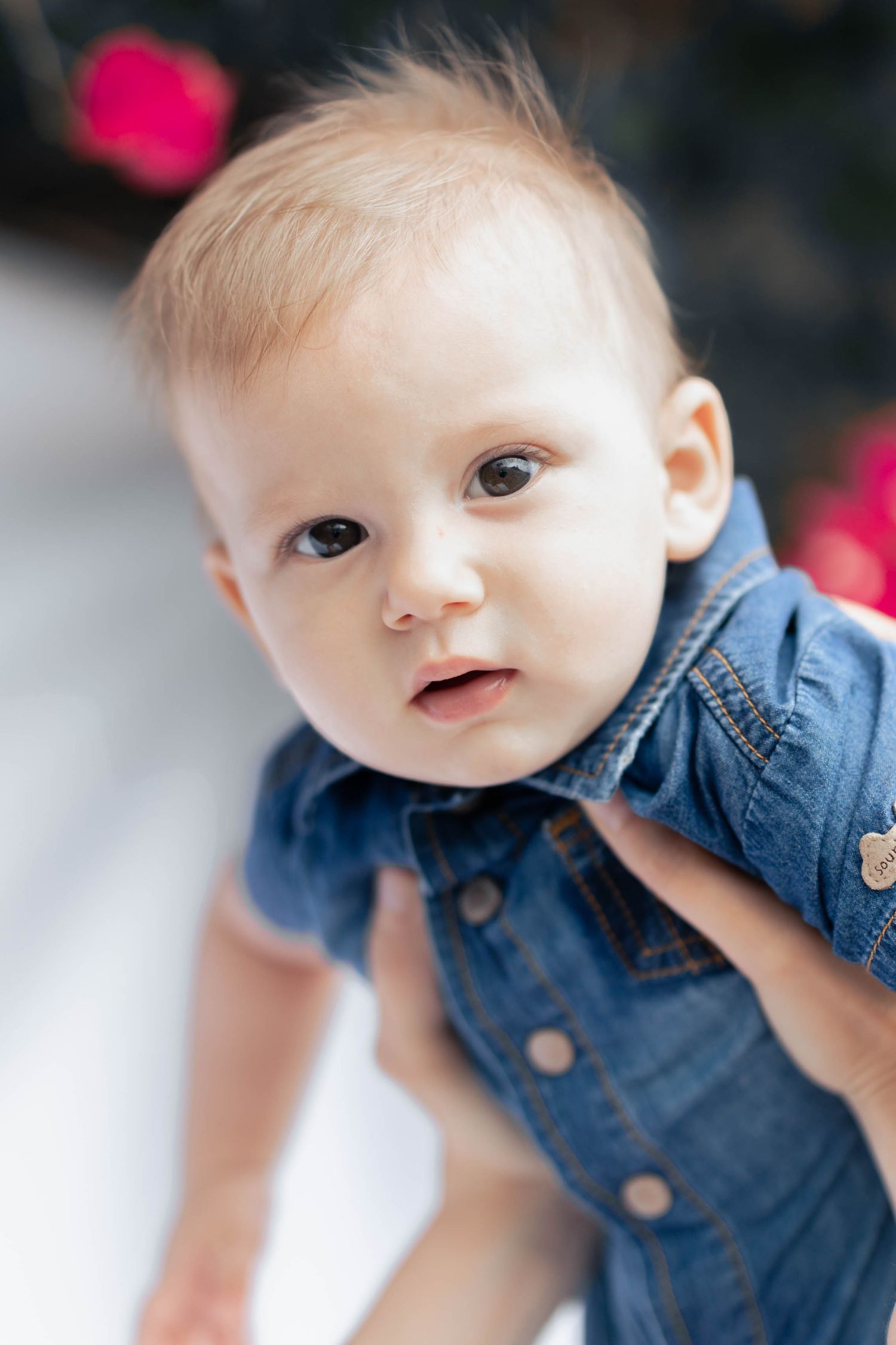 A baby in a denim shirt smiles while looking at the camera in a series of close-up portrait shots.