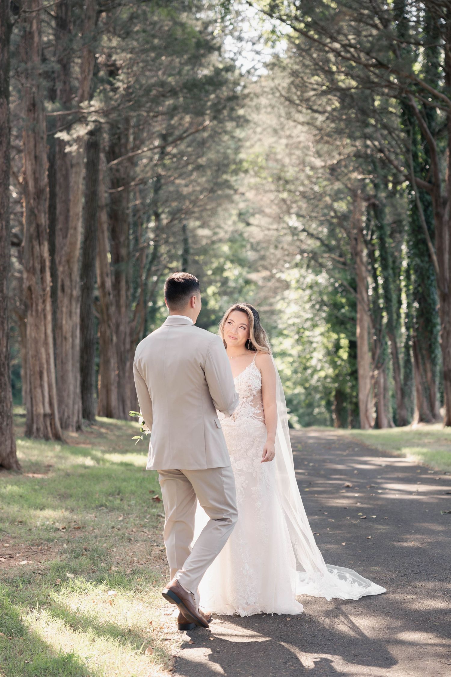 Dreamy woodland wedding scene with couple walking down a tree-lined path.