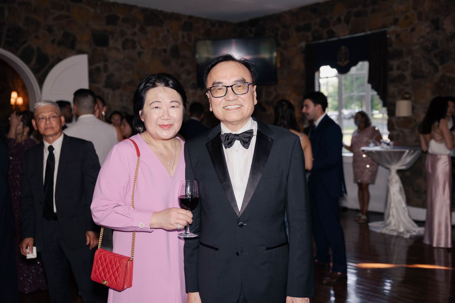 Wedding guests in formal attire gathered at an elegant indoor celebration.