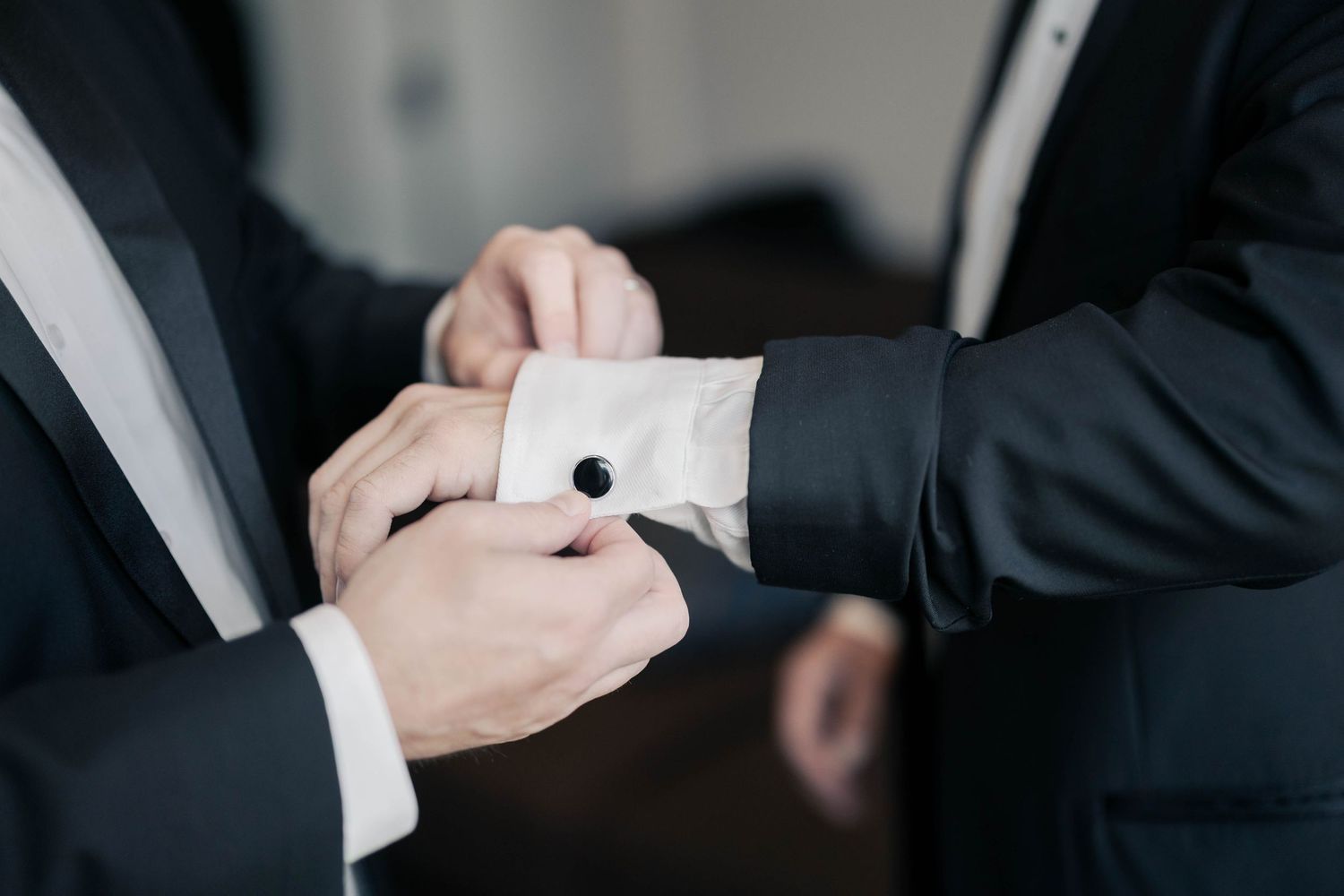 Detail shot of hands fixing formal shirt cuffs before ceremony.
