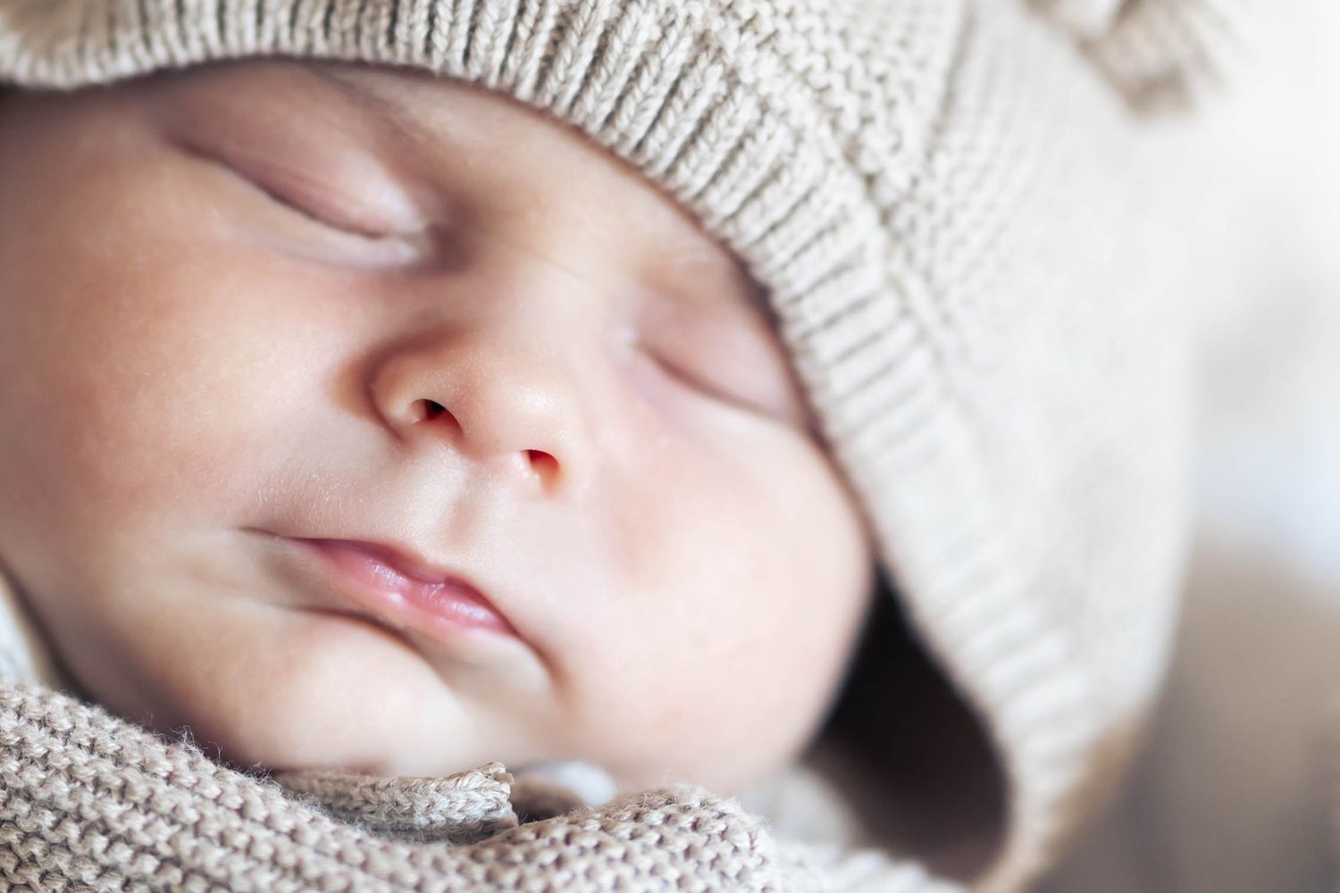 Gentle black and white portrait of a sleeping baby in a cozy knit cap.