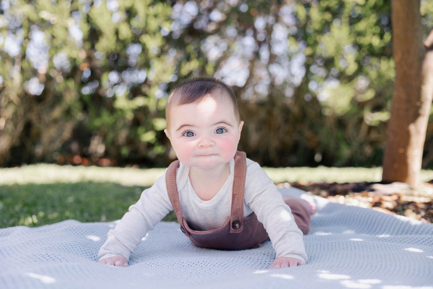 A collage of baby photos showcasing various developmental stages of infancy on a light colored blanket outdoors.