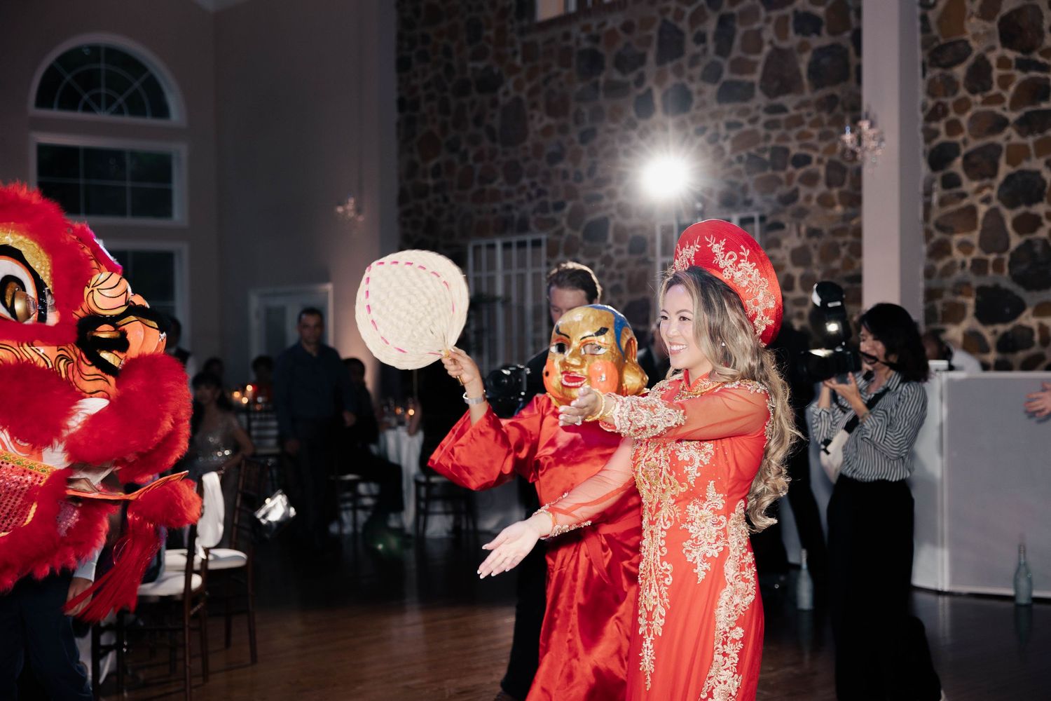 Lion dancers in vibrant red costumes perform at a festive indoor celebration.
