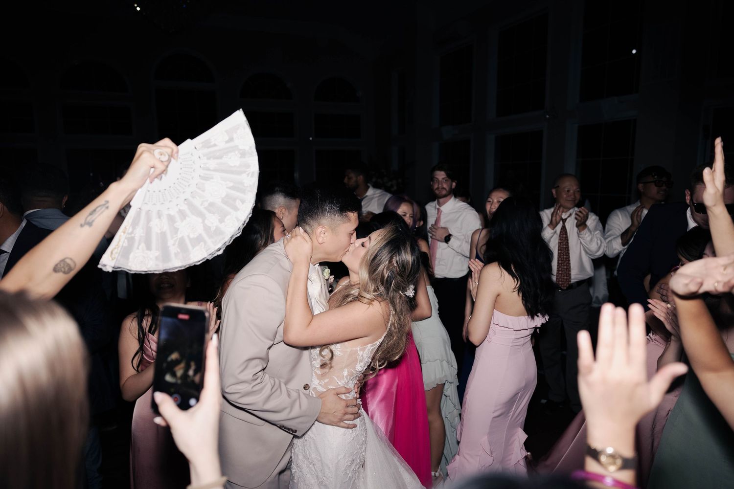 Silhouettes of wedding couple and guests dancing in a darkened reception venue.