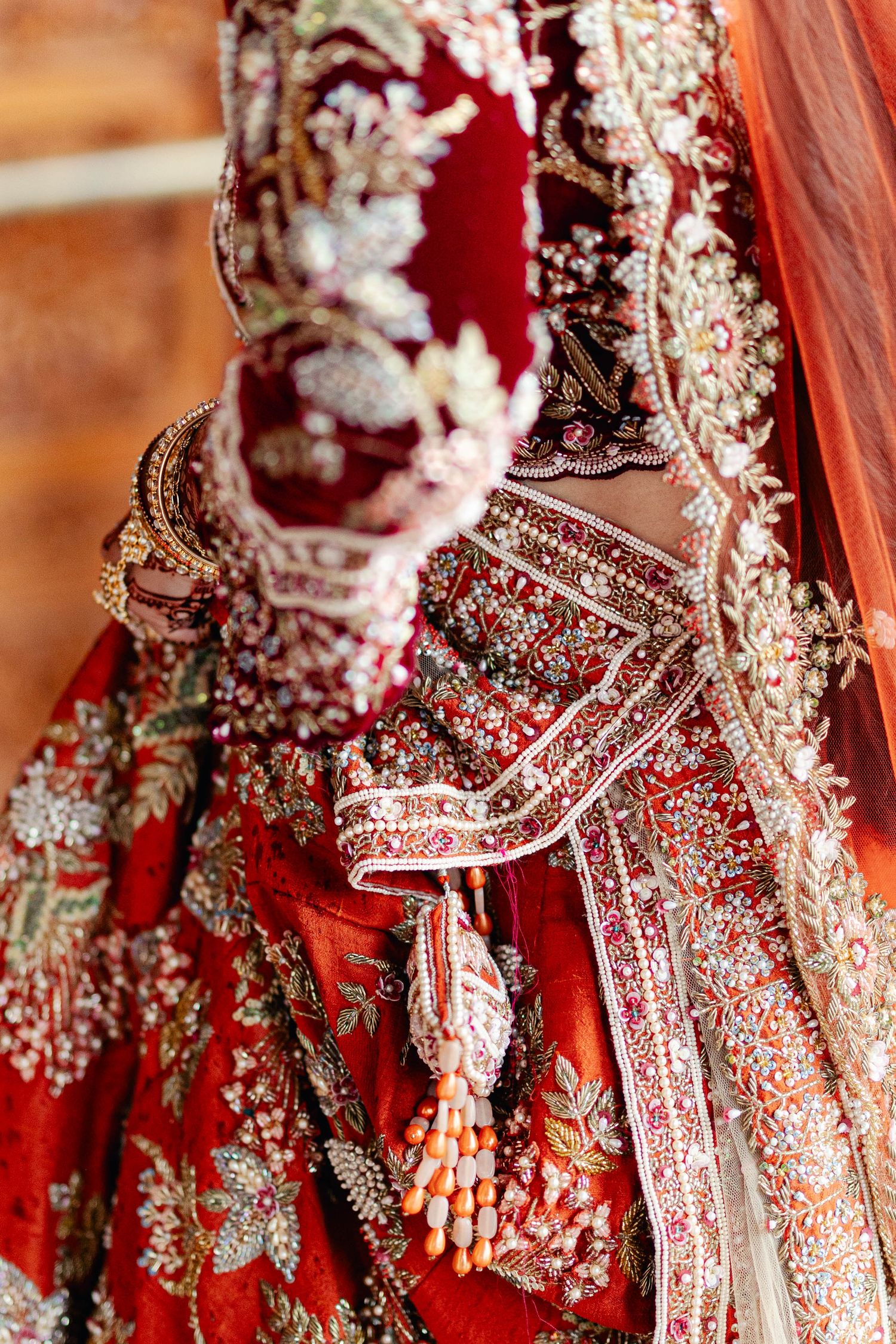 Detailed view of traditional Indian bridal attire showing intricate red and gold embroidered lehenga with matching jewelry.