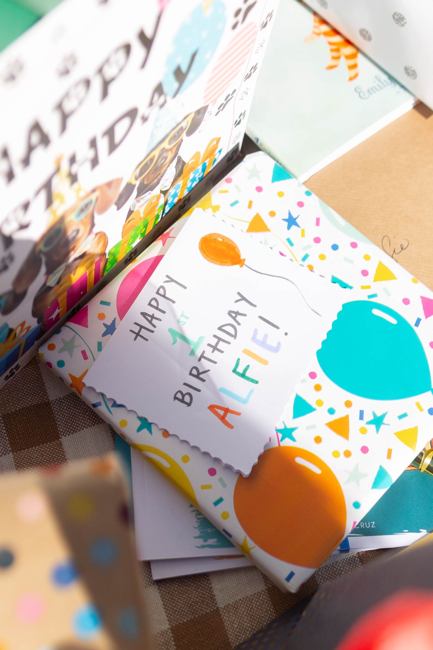 Colorful birthday cards with festive confetti and balloon patterns arranged in a row on a blurred surface.