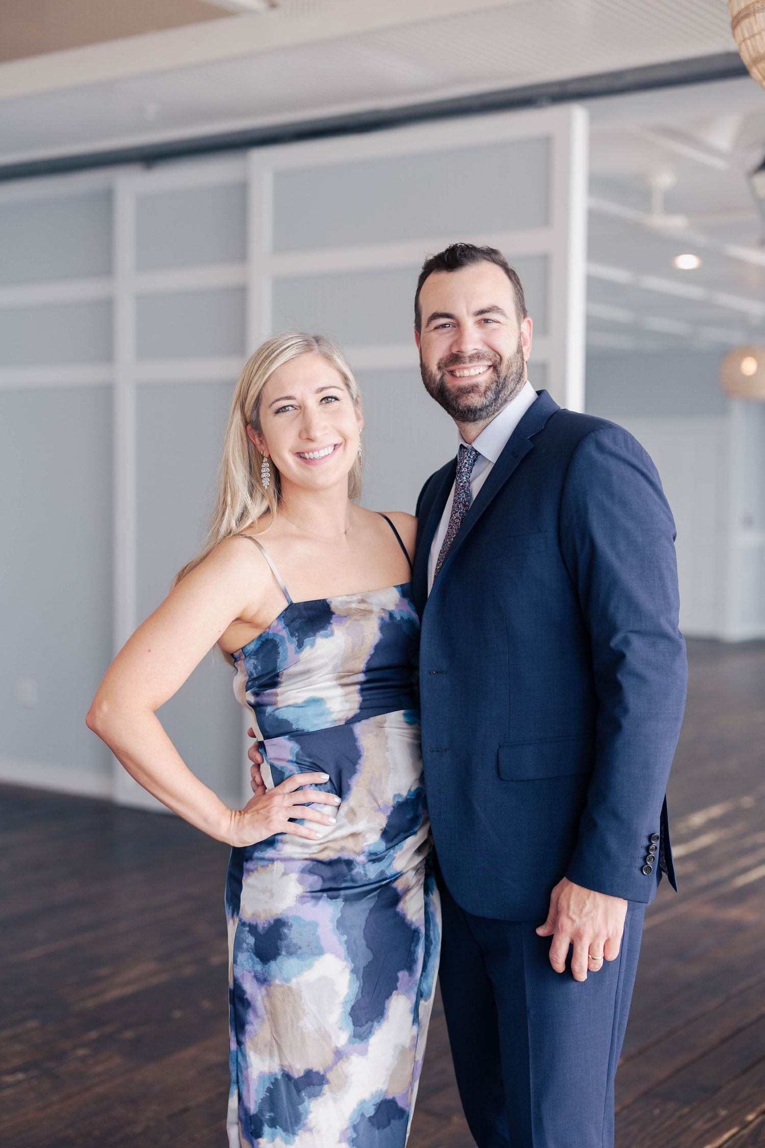Engagement photos featuring couple in formal attire against modern interior backdrop.