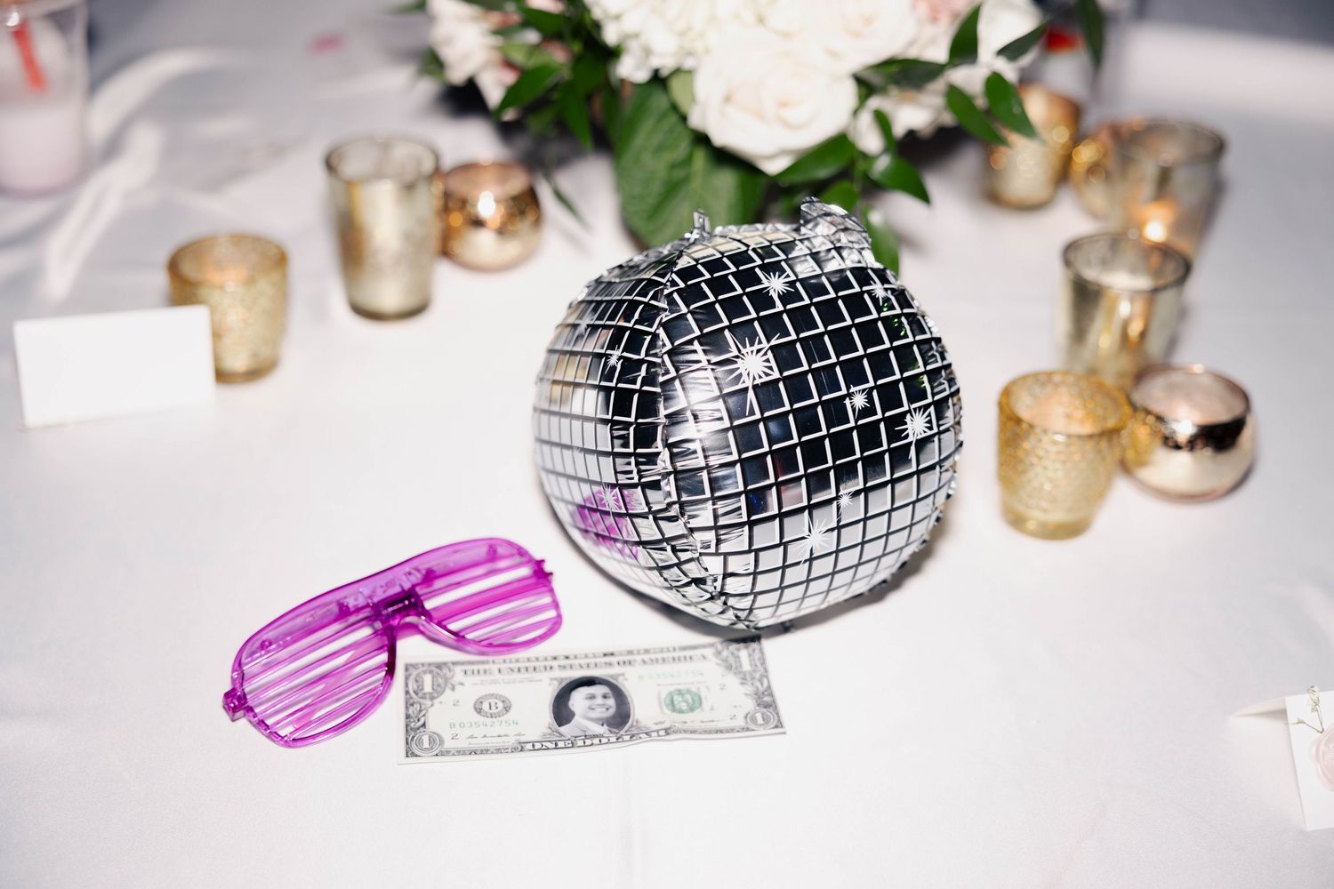 Wedding reception table decorations with disco ball, floral centerpieces and candles.