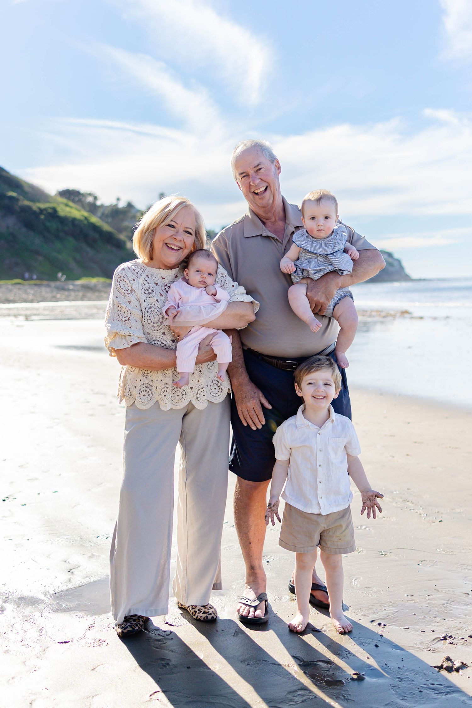 Family enjoying a sunny day at the beach together with sand and ocean waves in the background.