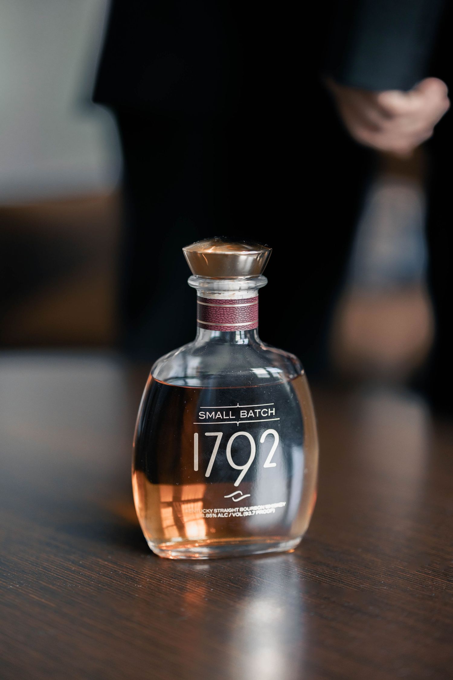 Glass bottles of 1792 Bourbon displayed on dark wooden surface.