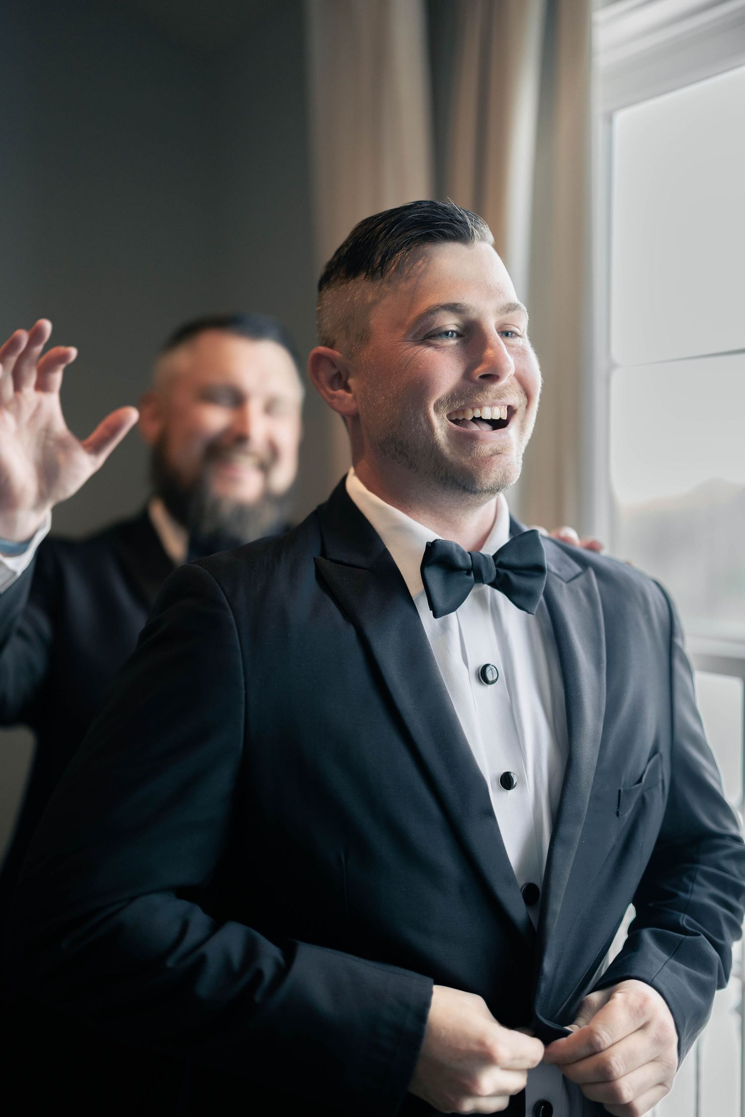 Wedding party members in black tuxedos sharing a joyful moment together.