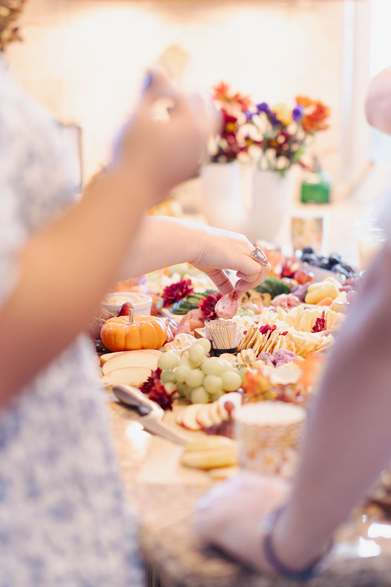 A beautifully arranged charcuterie board with grapes, pumpkins, and various appetizers being served at an elegant event.