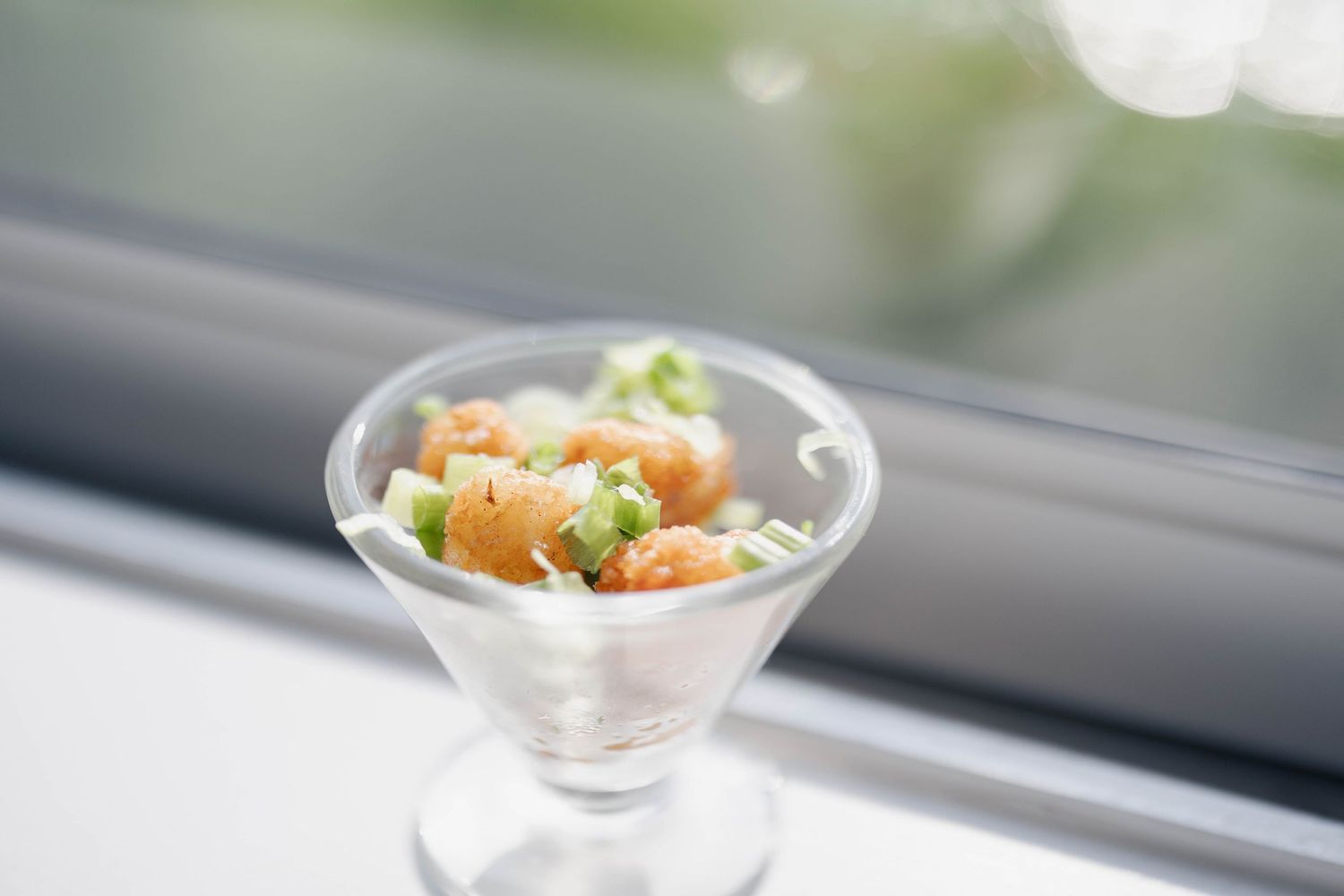 Close-up of elegant appetizer dishes arranged on a bright windowsill.