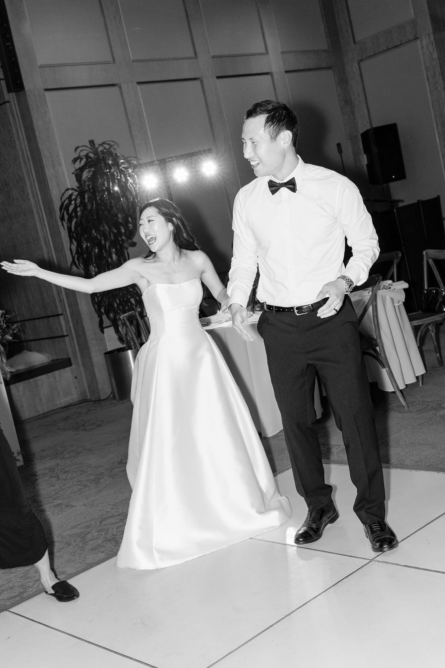 Bride and groom share a joyful first dance at their wedding reception in black and white photo.