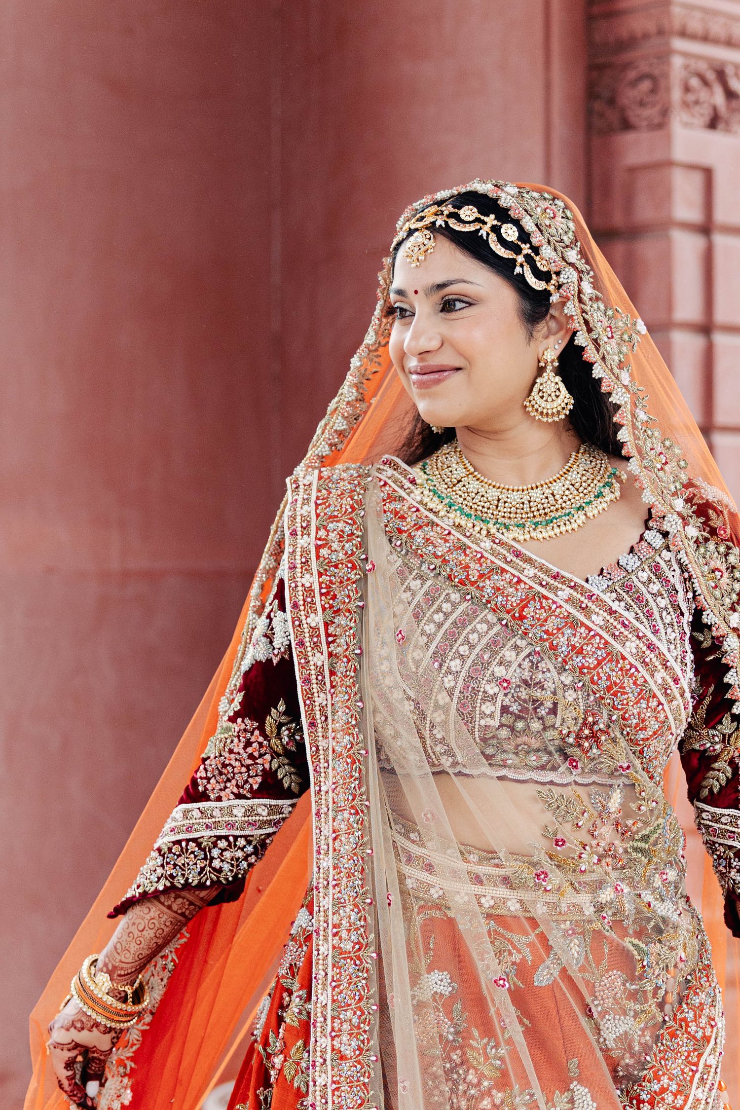 Beautiful traditional Indian bridal attire featuring an ornate orange and gold lehenga with intricate embroidery and jewelry.
