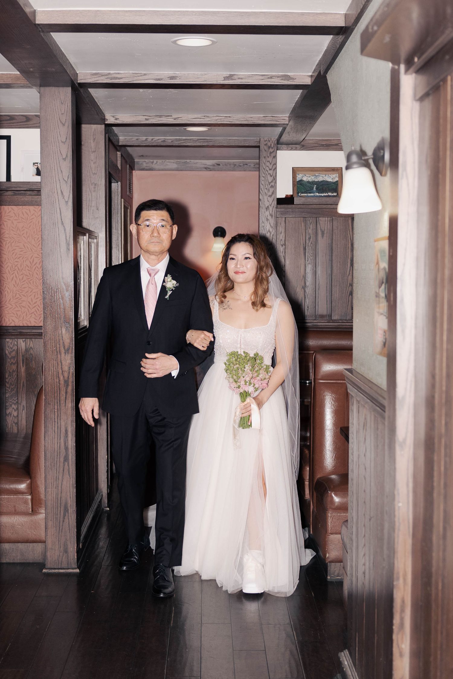 Wedding party walking down dark wood-paneled hallway at venue.