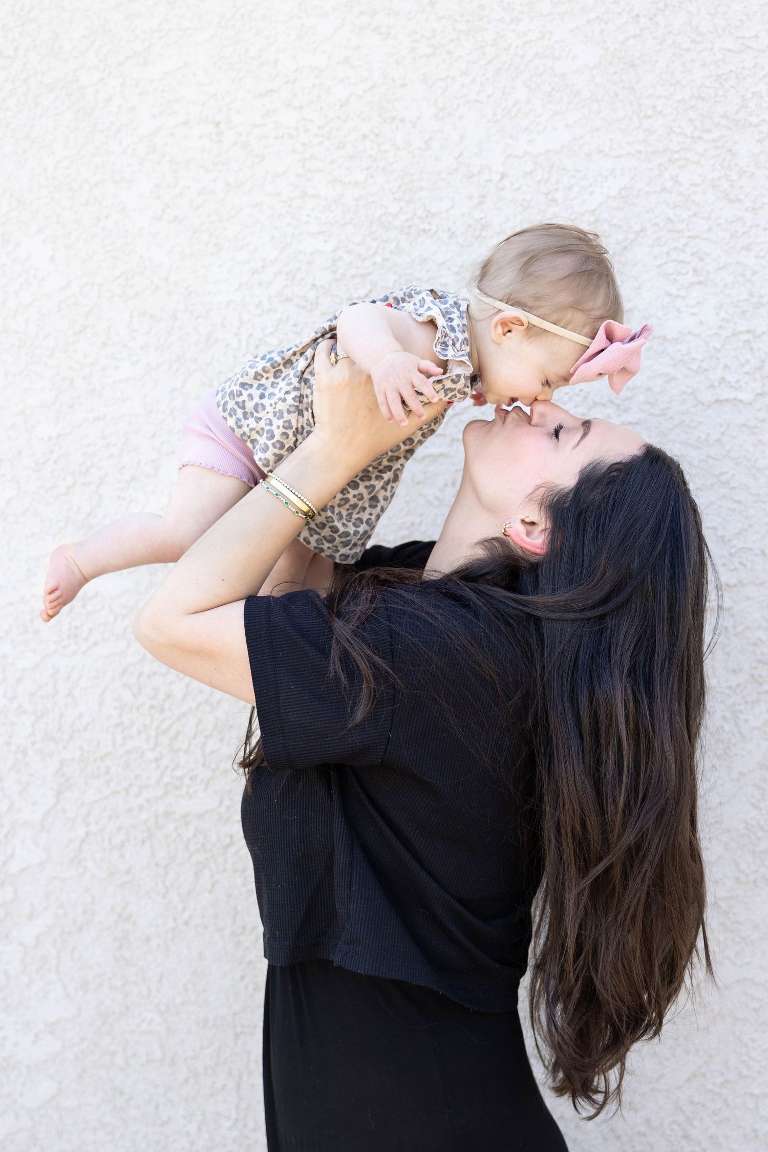 Playful moment between mother and baby against white background.