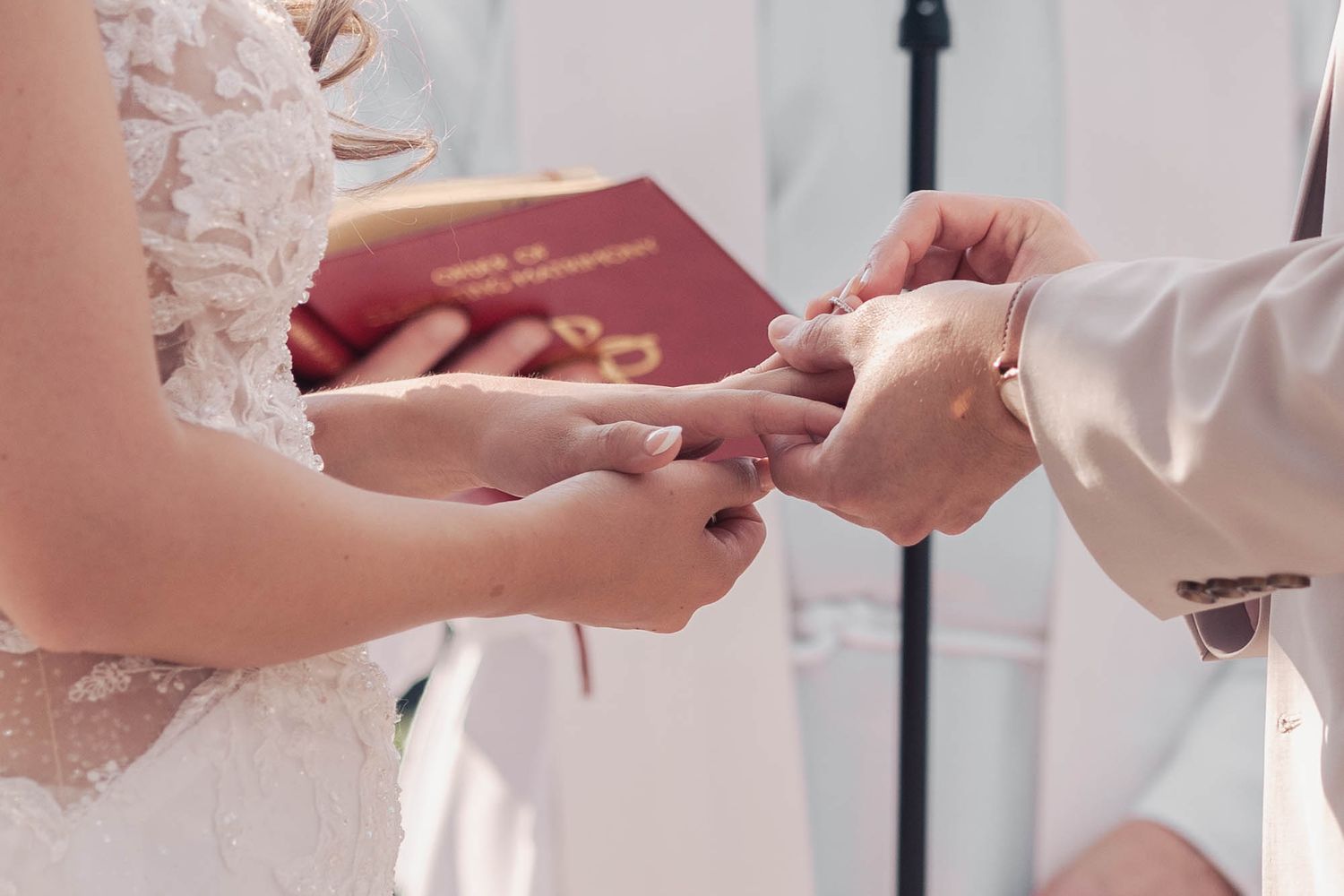 Close-up of hands exchanging rings during wedding ceremony.