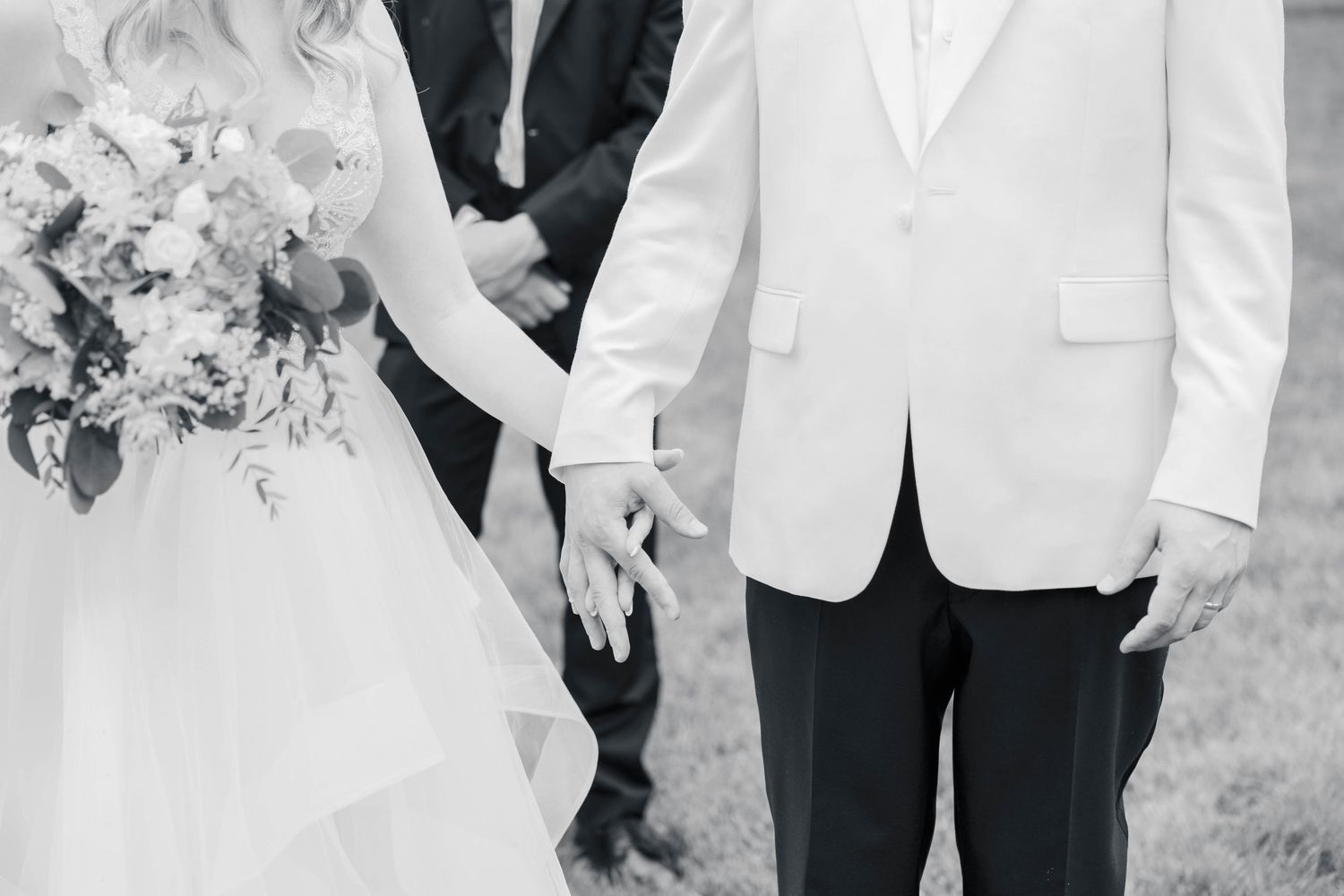 A couple in wedding attire poses with their wedding party in black and white formal wear at an outdoor celebration.