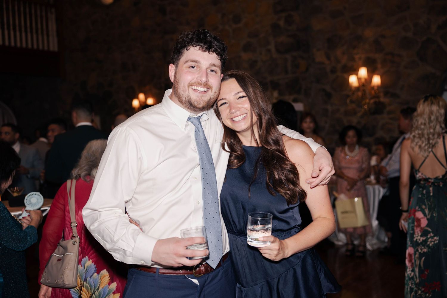 Couples and guests celebrating at an elegant stone-walled venue during a wedding reception.