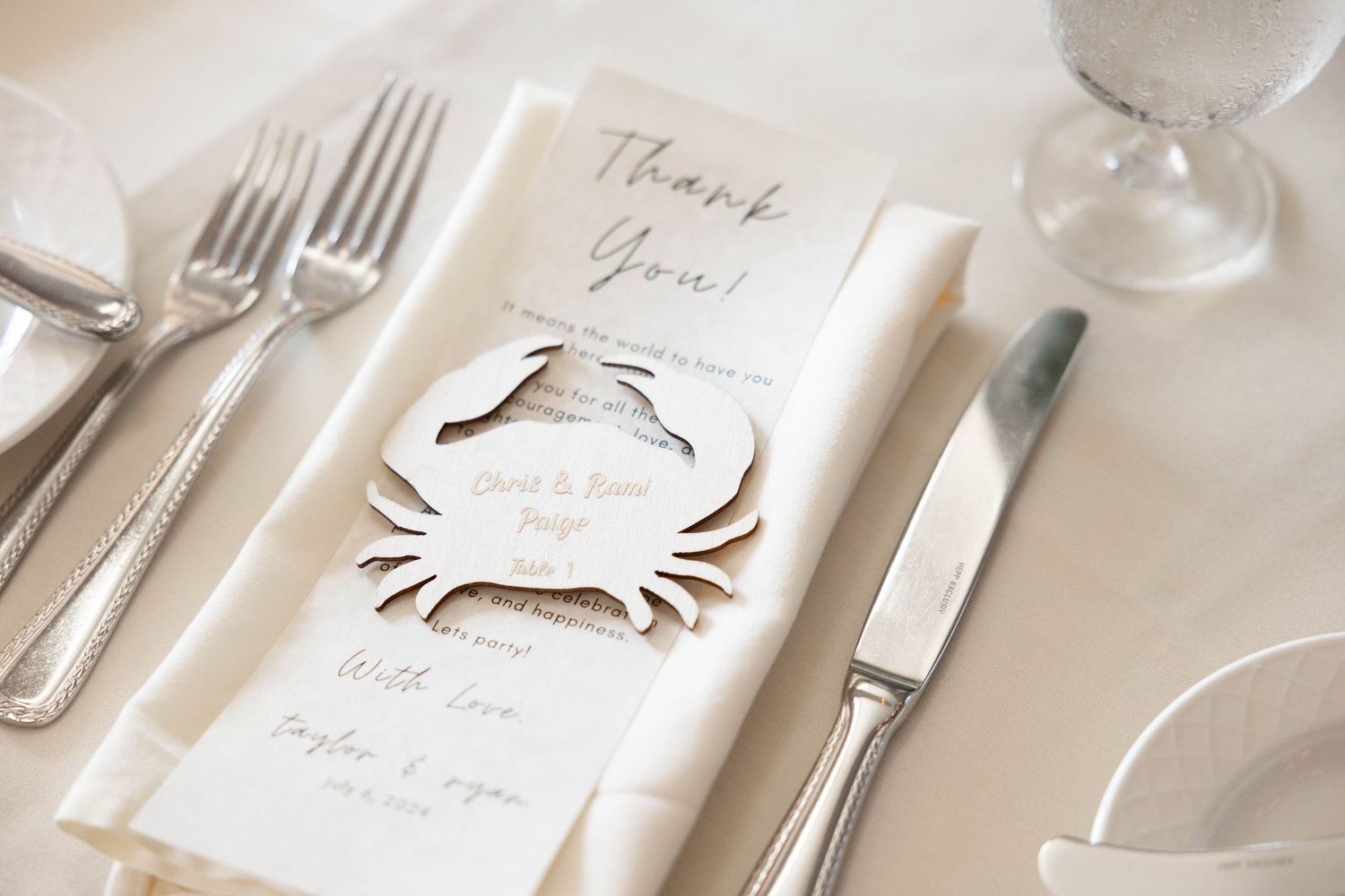 Wedding place settings with elegant thank you cards and silverware on white tablecloths.