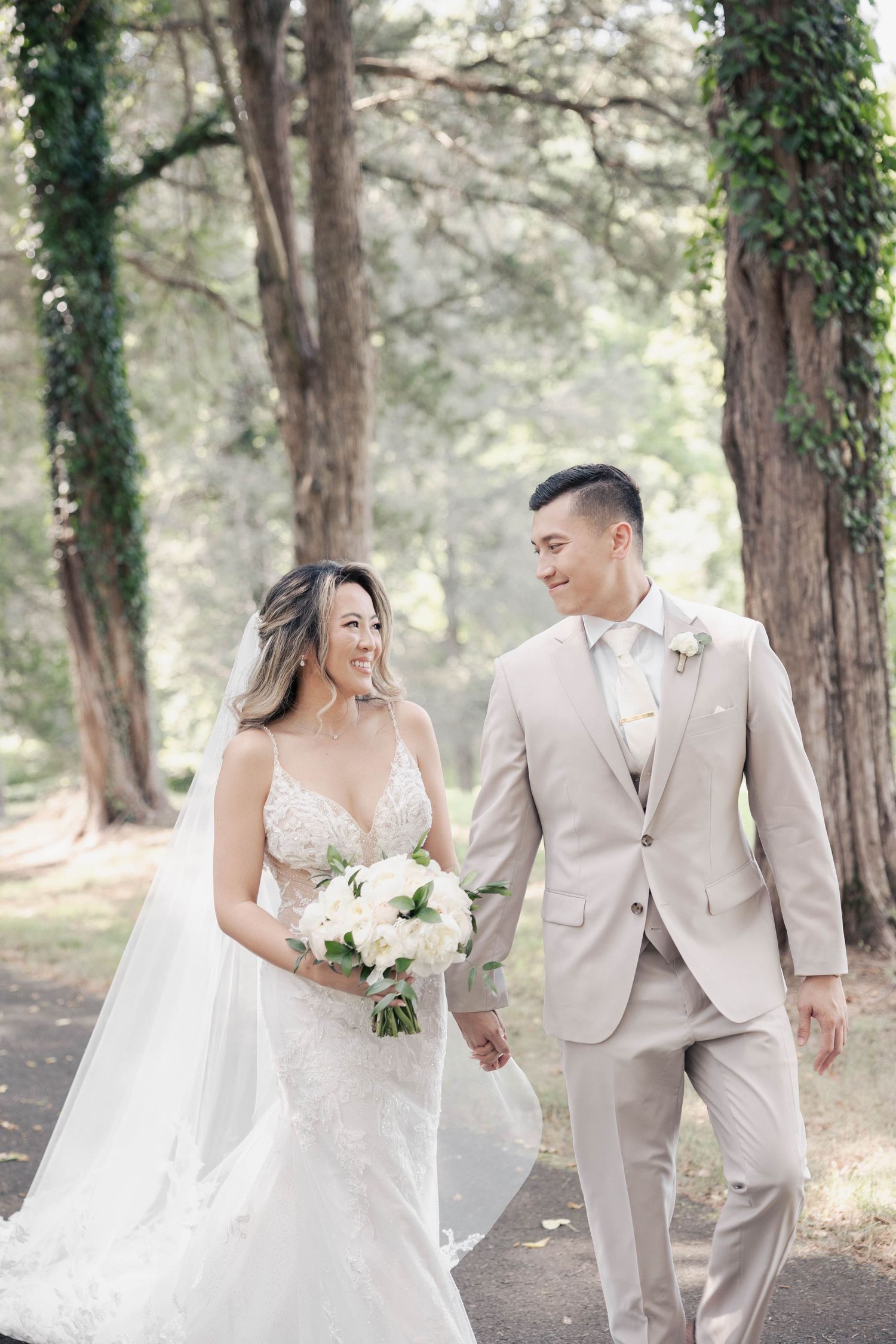 Joyful wedding couple walking hand in hand through a pine forest path.