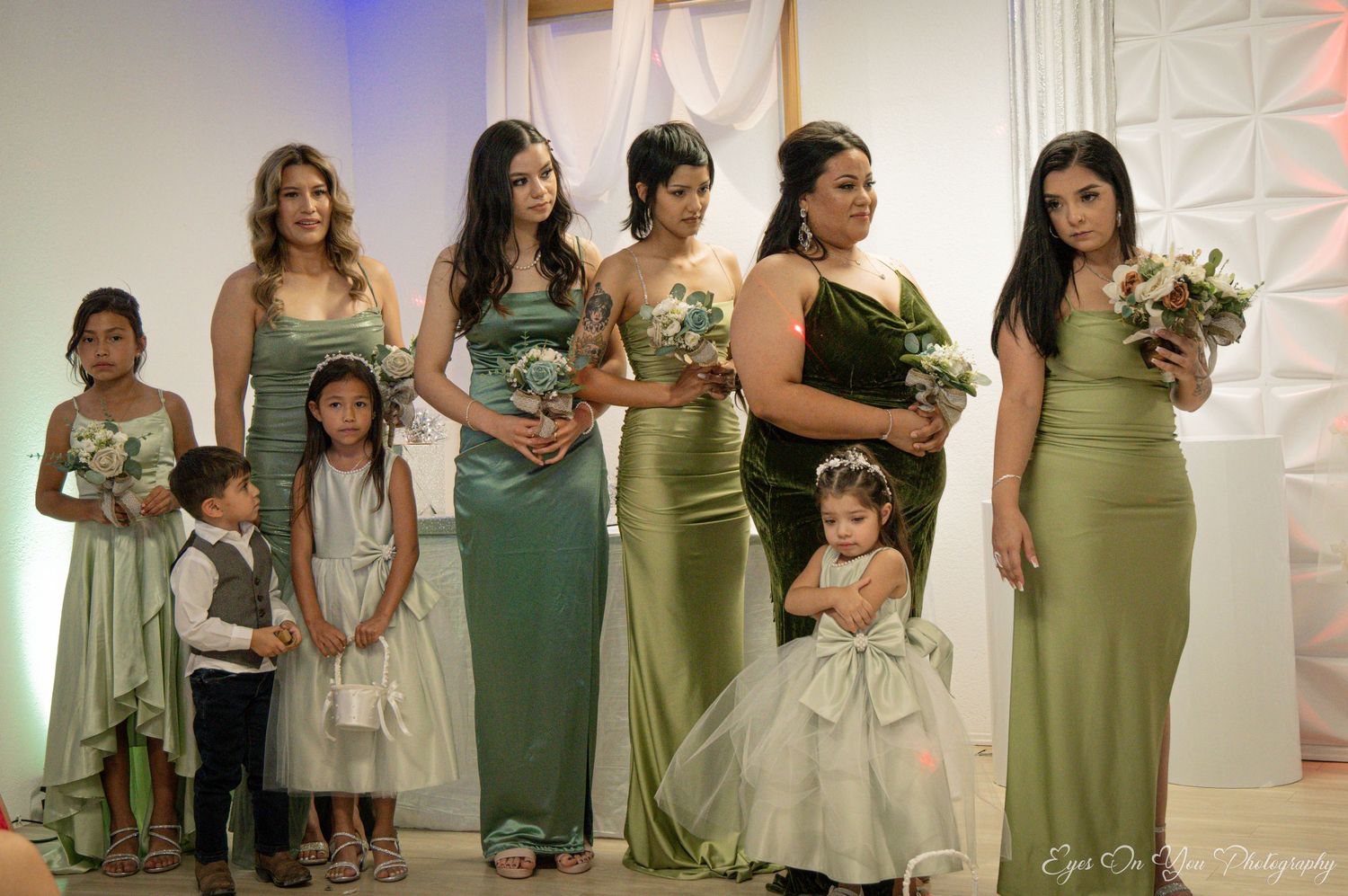 Wedding party lined up in elegant sage green bridesmaid dresses and formal attire.