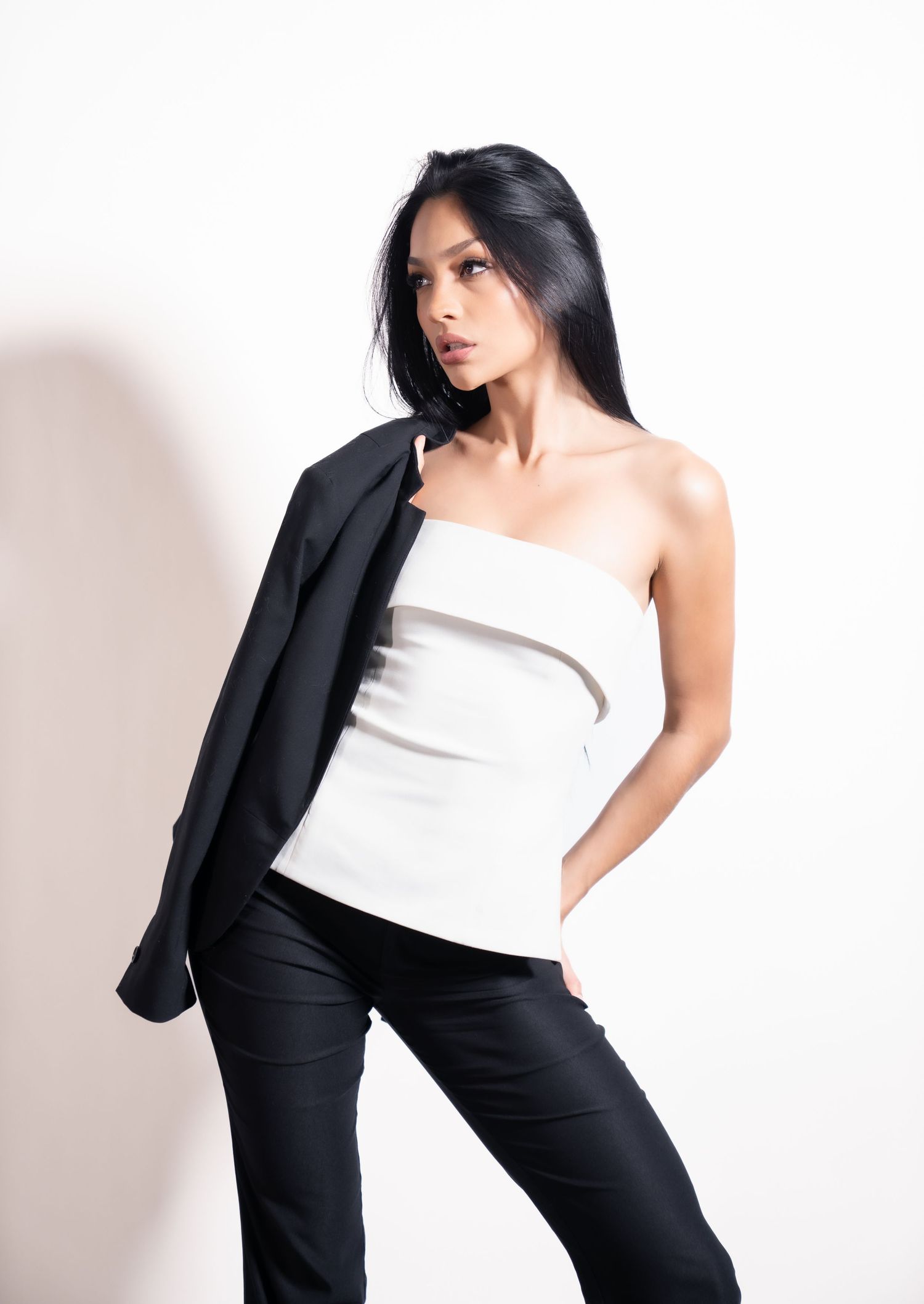 A fashion model in black pants and white top strikes dynamic poses against a white backdrop in a photo series.