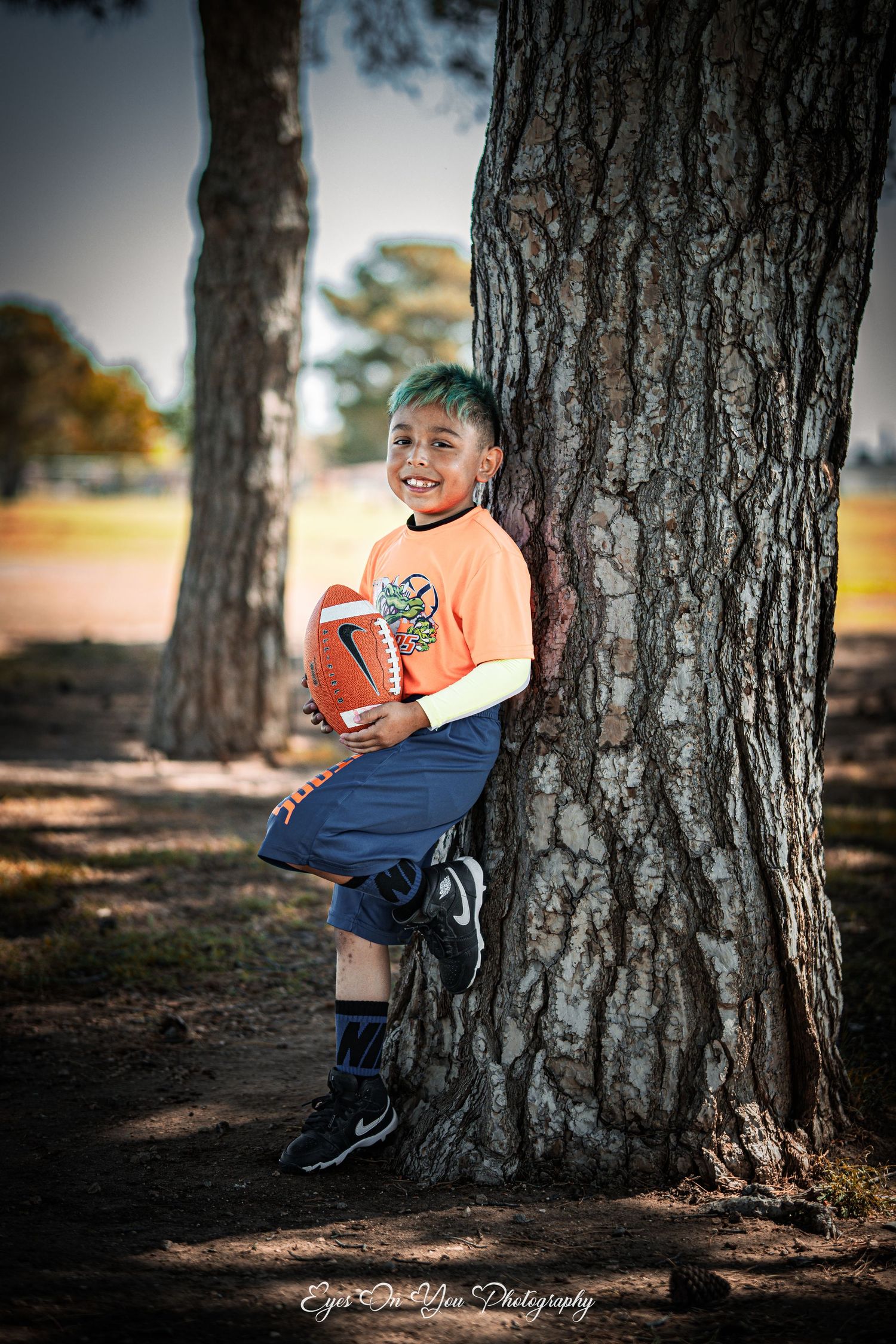 A series of outdoor portraits showing a child in an orange shirt and blue pants playing near large tree trunks.