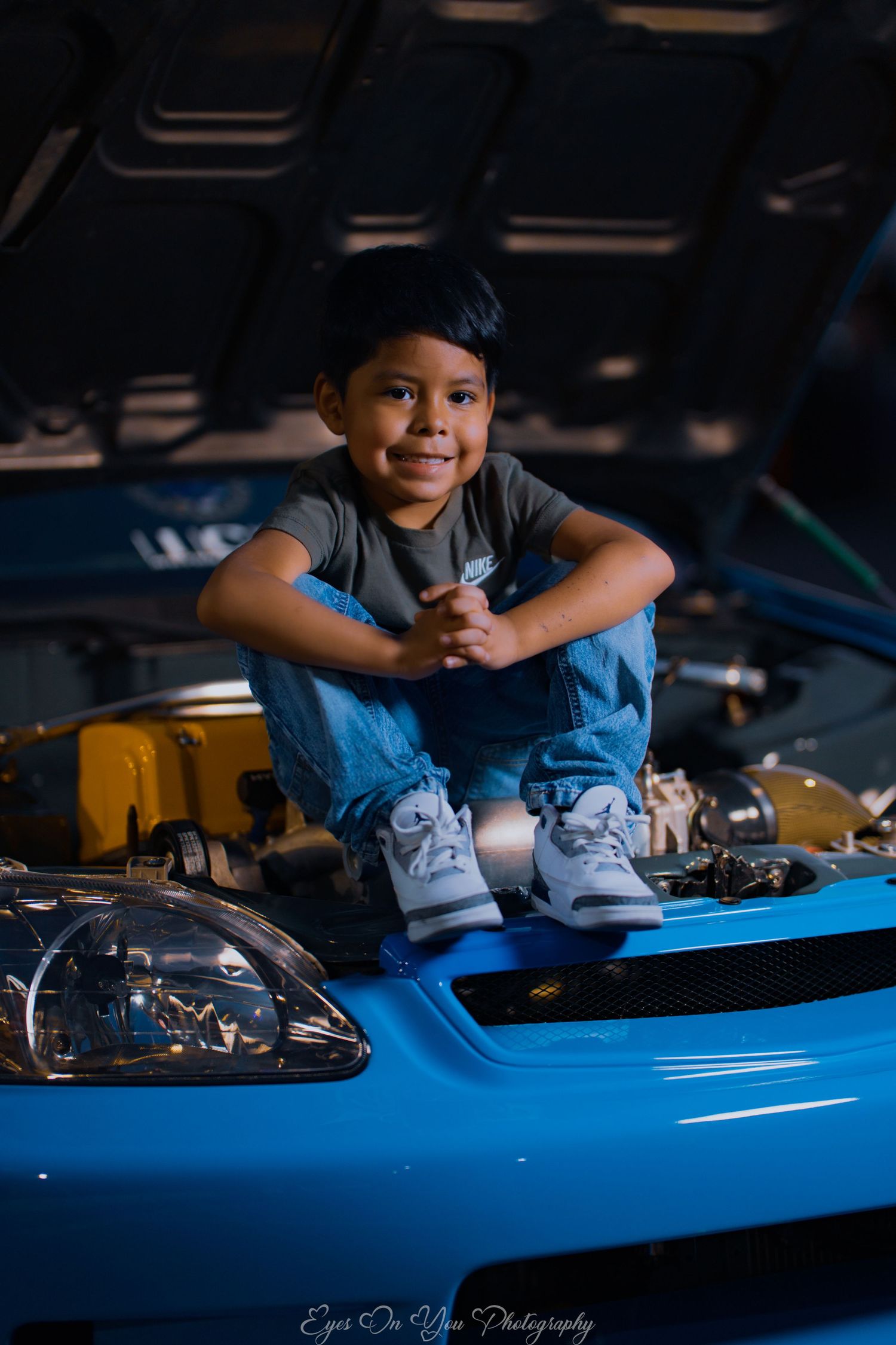 A child leans over a bright blue car hood during an automotive photo session.
