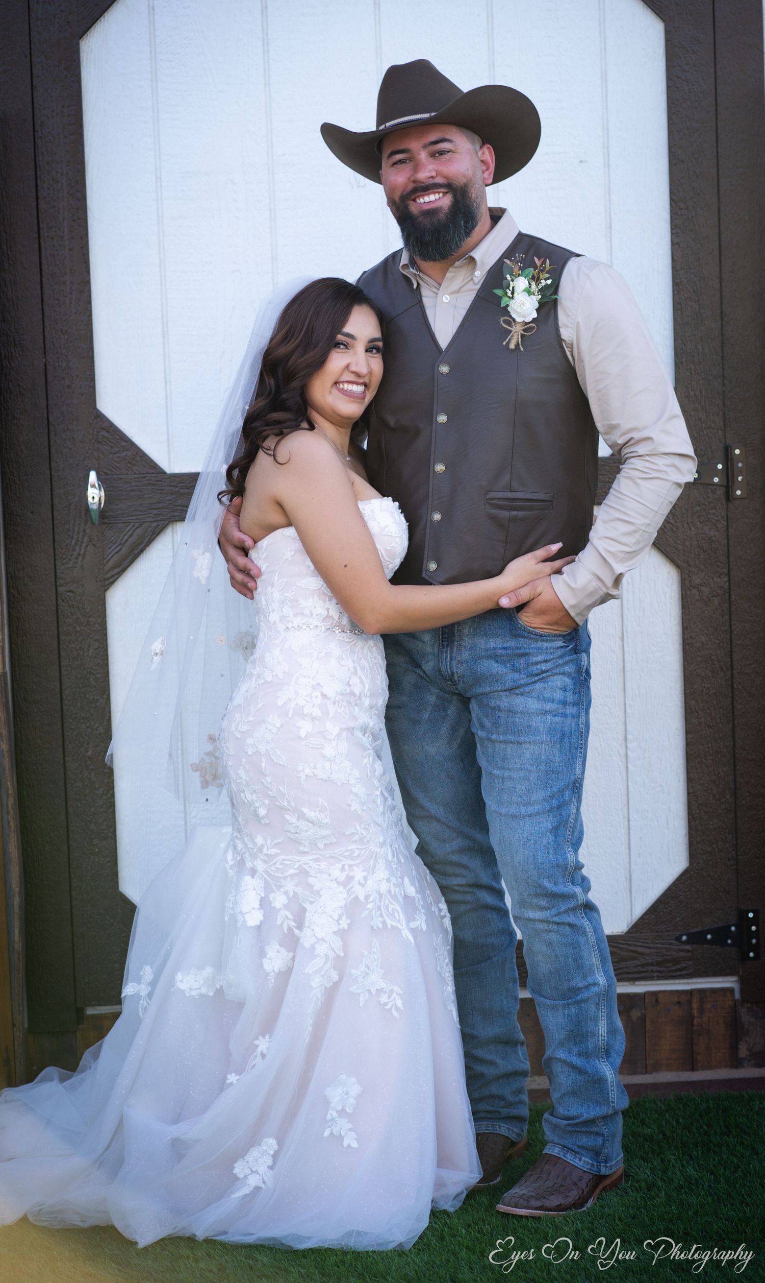 Western-themed wedding photo featuring a bride in lace and groom in cowboy attire.