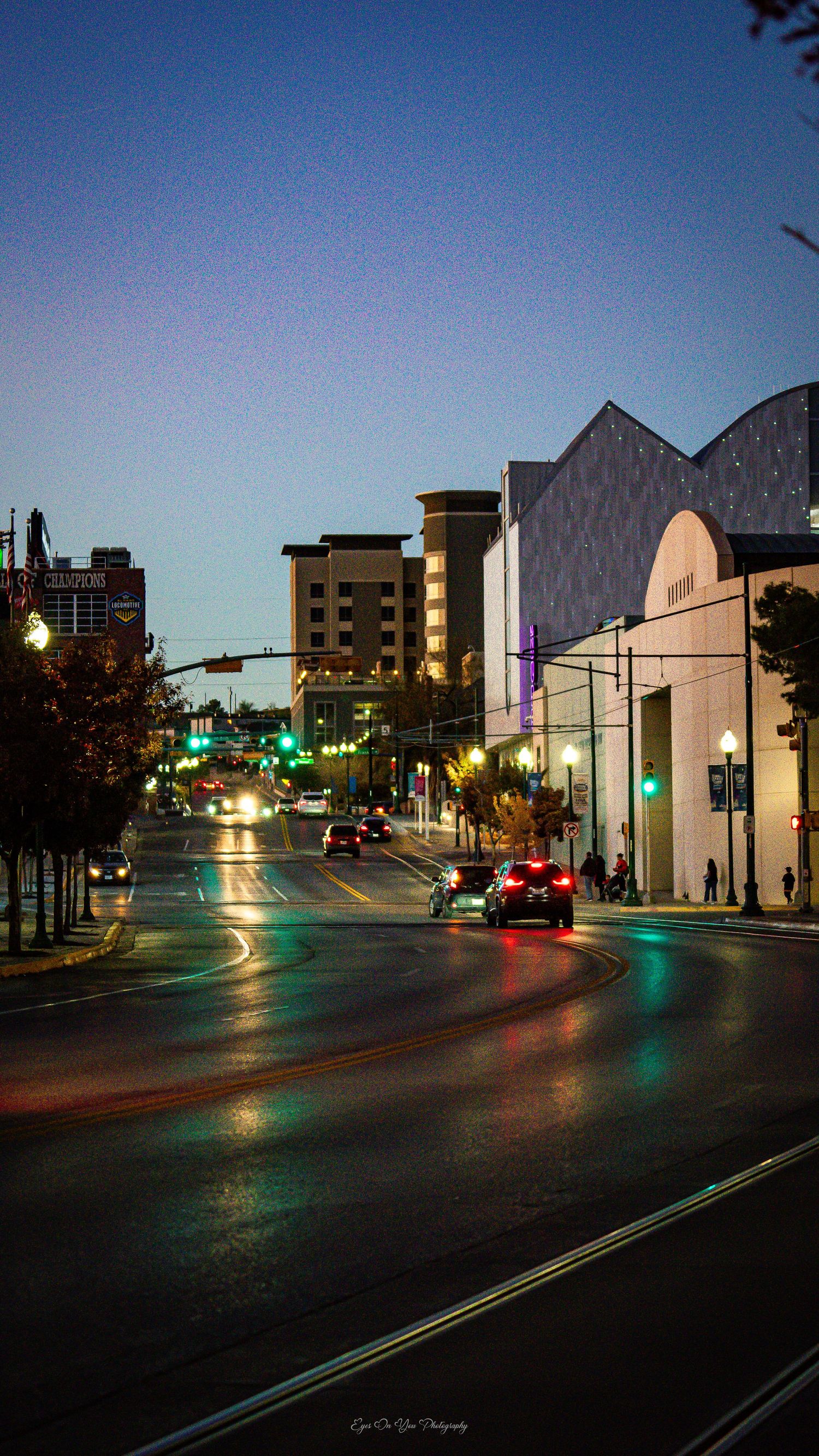Urban street scene at twilight with white building facade and traffic lights.