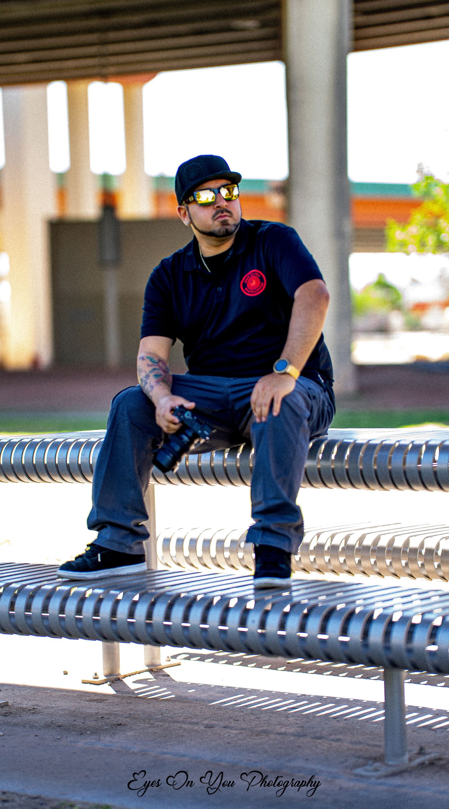 Individual relaxing on metallic bench under covered outdoor area.