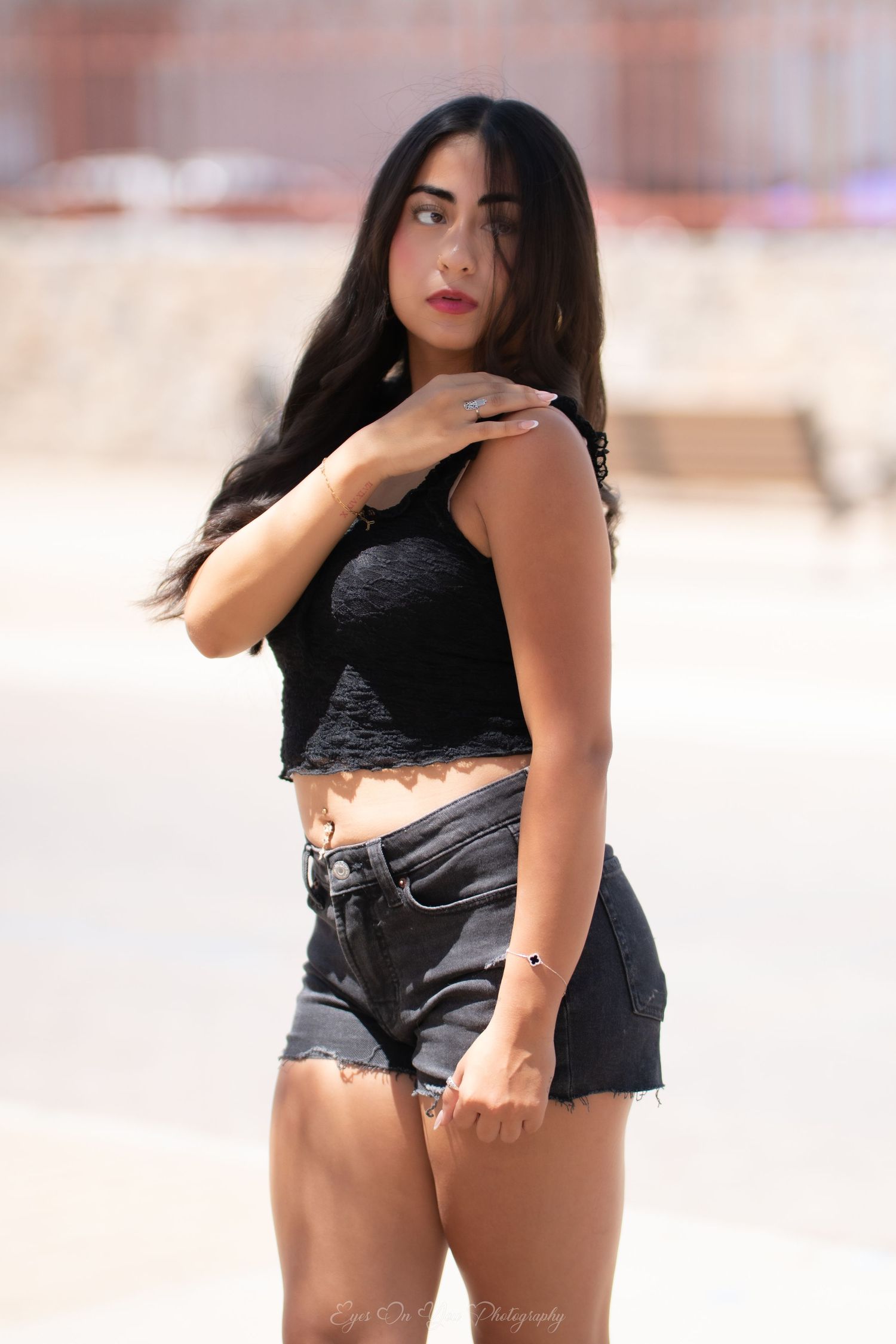Fashionable summer street style with a black crop top and denim shorts against an urban background.