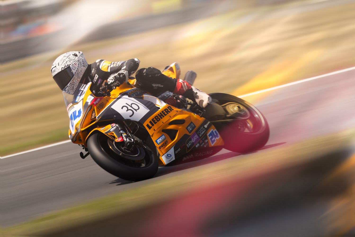 Motorcycle racers navigate a turn at golden hour creating dramatic racing action.