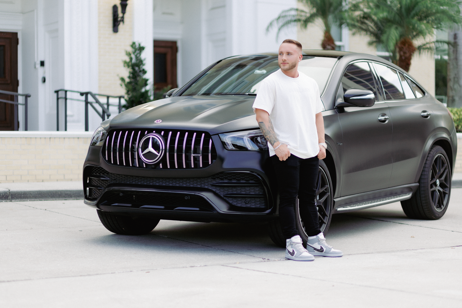A sleek black Mercedes-Benz GLE Coupe AMG parked outside a luxury building with palm trees.