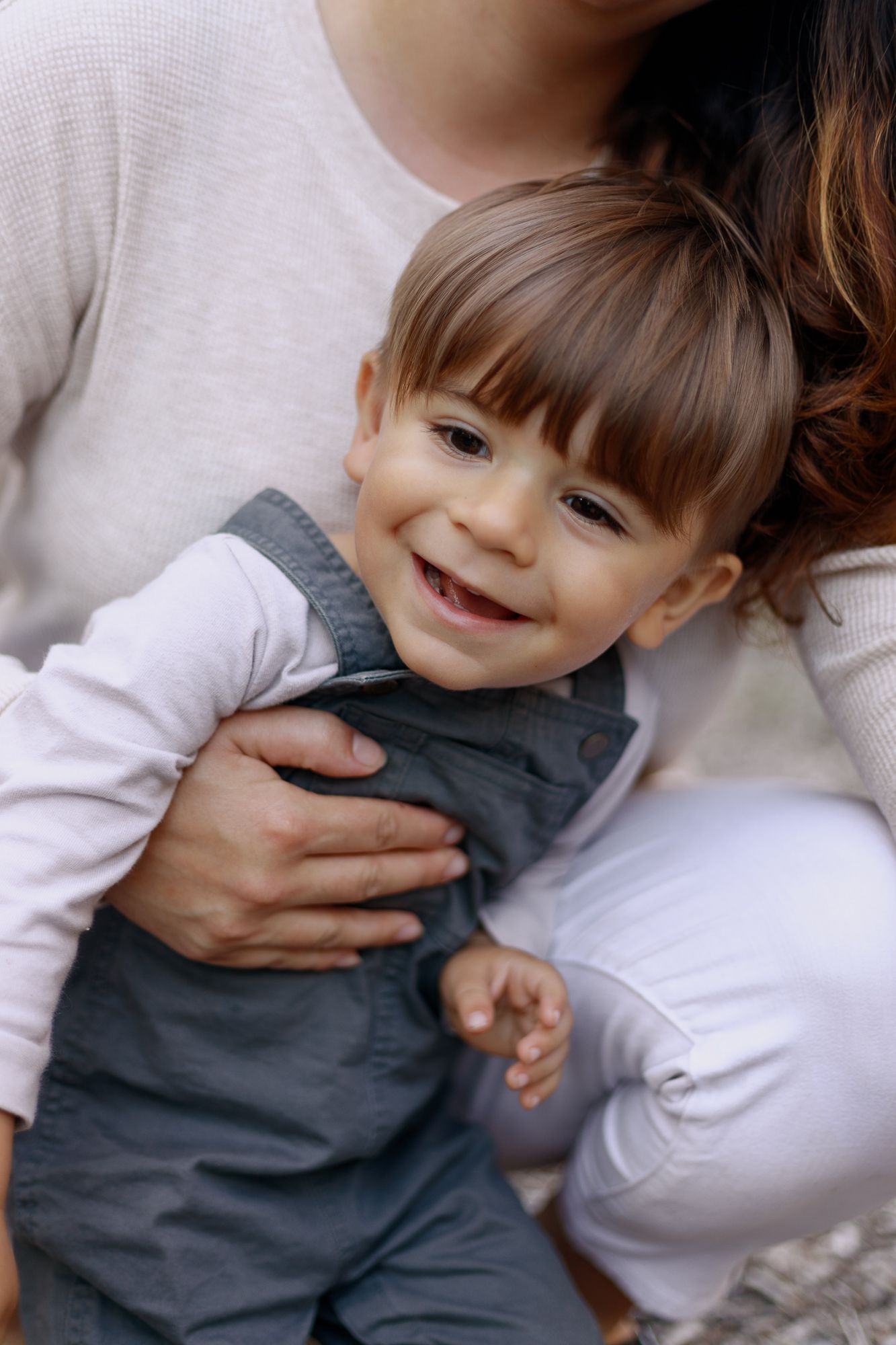 Toddler is smiling while his mommy holding him