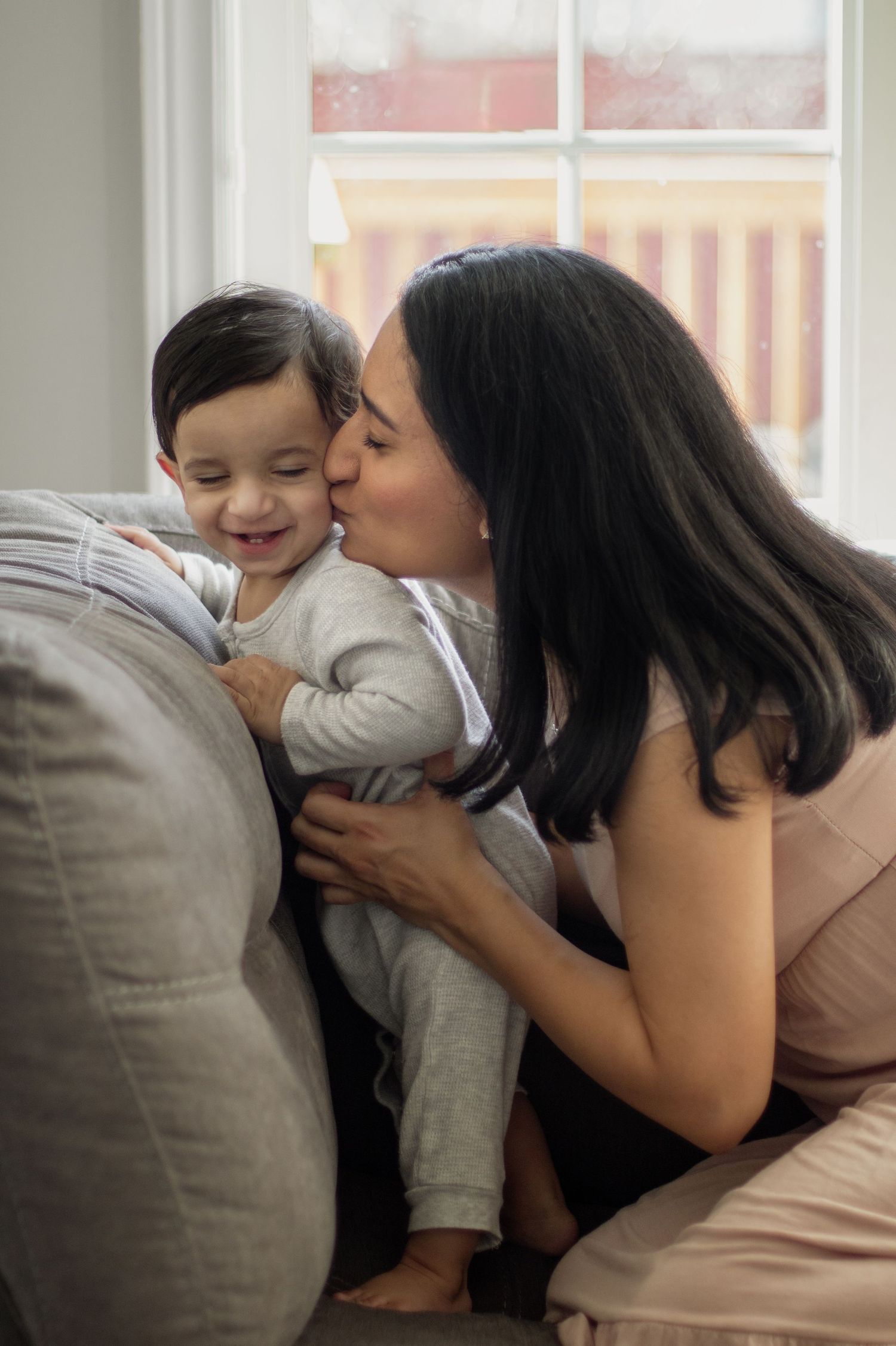 This image shows a mom kissing her toddler.