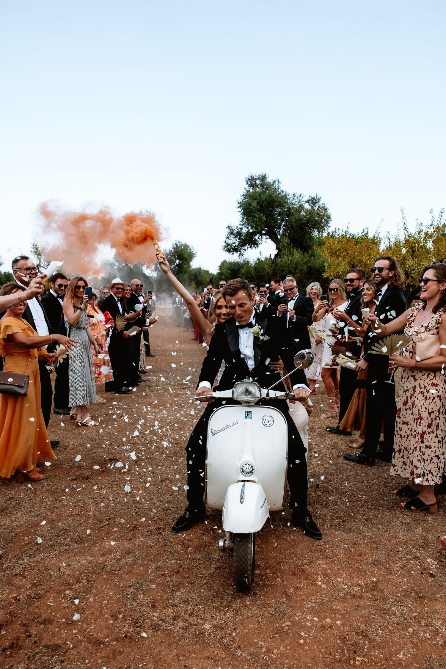 Wedding celebration with vintage Vespa scooters and colorful smoke bombs creating a festive atmosphere.
