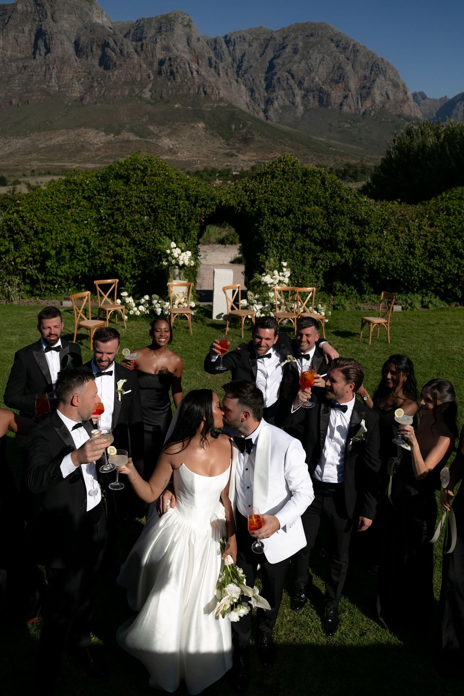 Wedding celebration with guests gathered outdoors against dramatic mountain backdrop at scenic vineyard venue.