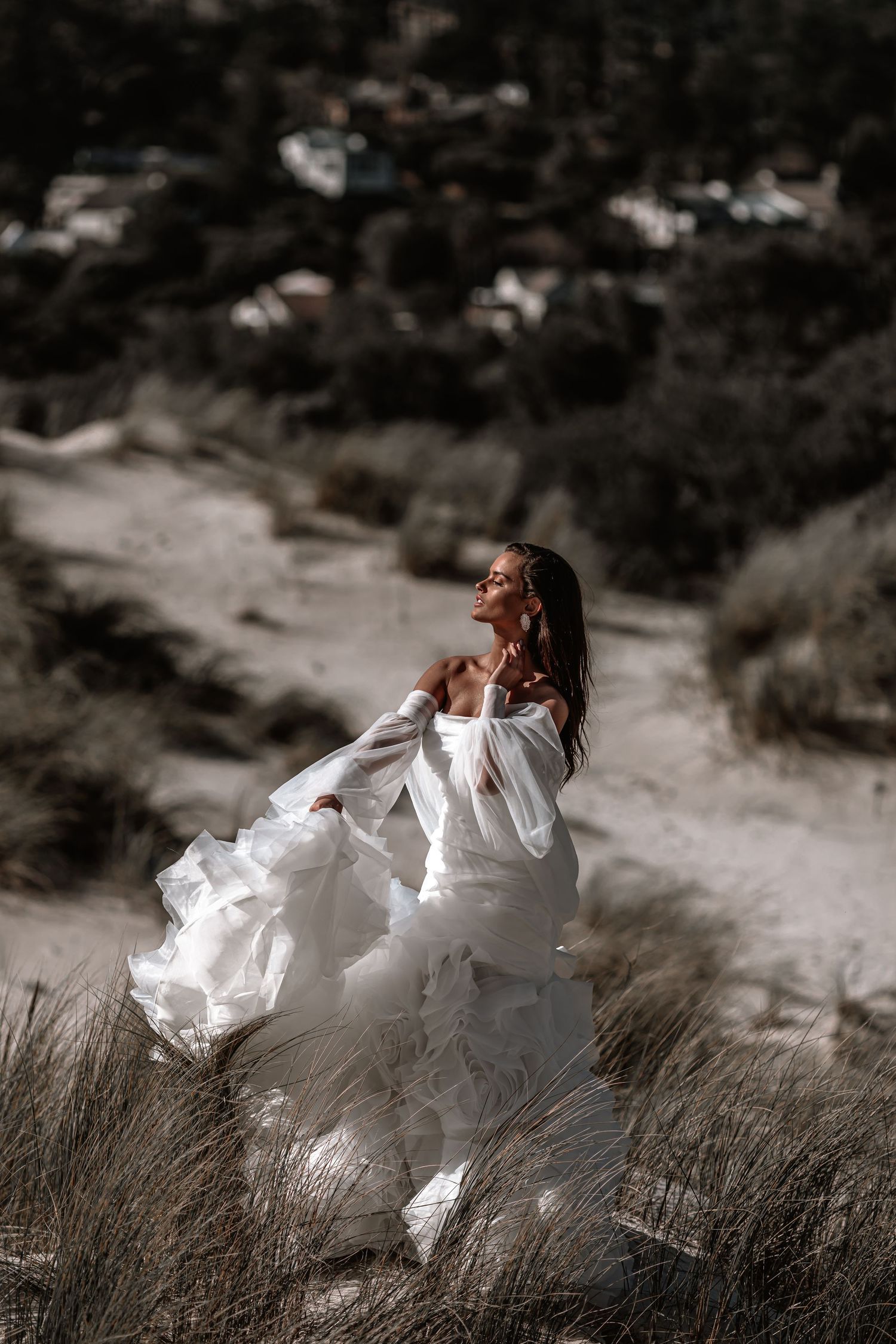 A person in a flowing white dress poses dramatically against a desert landscape.