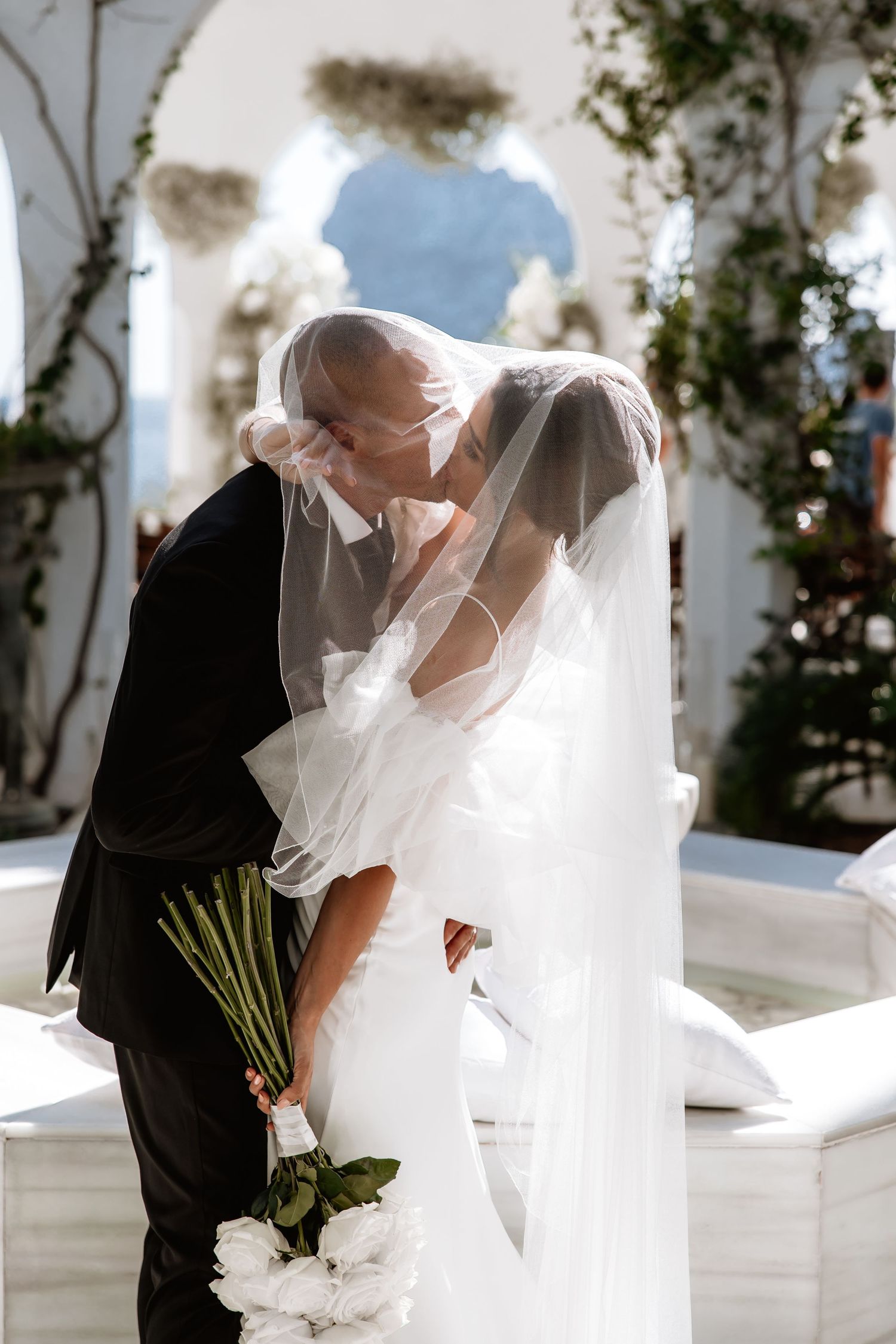 A romantic wedding couple shares intimate moments among white columns in a series of artistic photos.