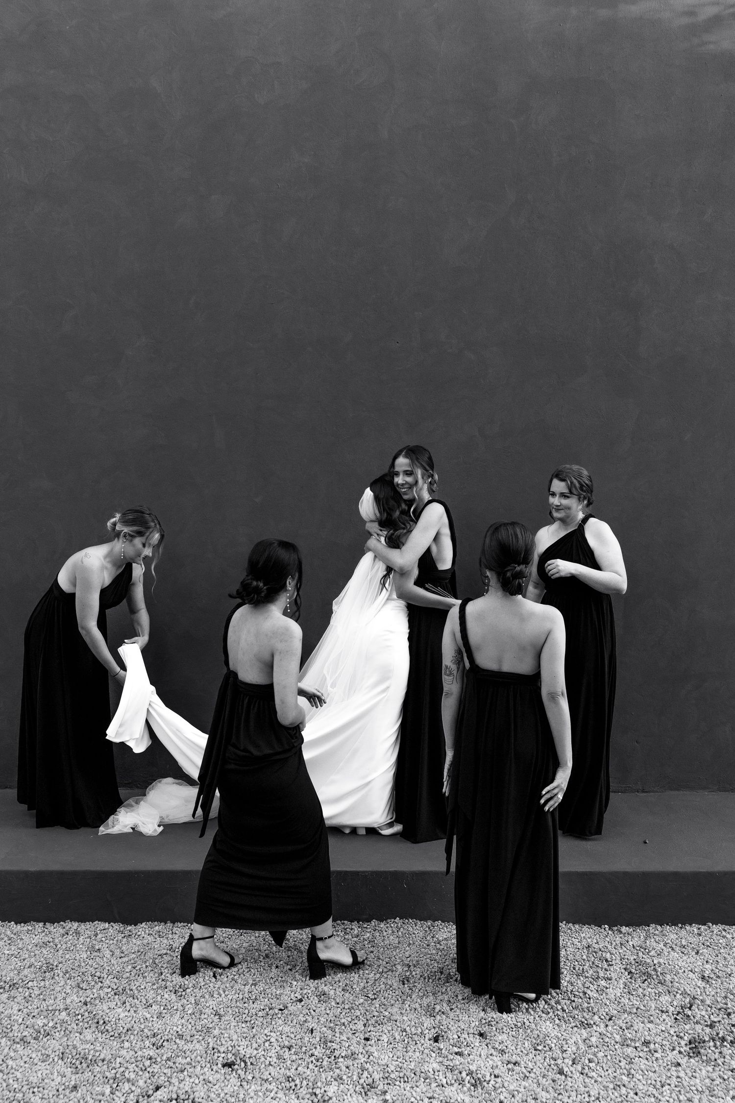 Artistic black and white sequence showing figures in dark dresses against a gray wall.