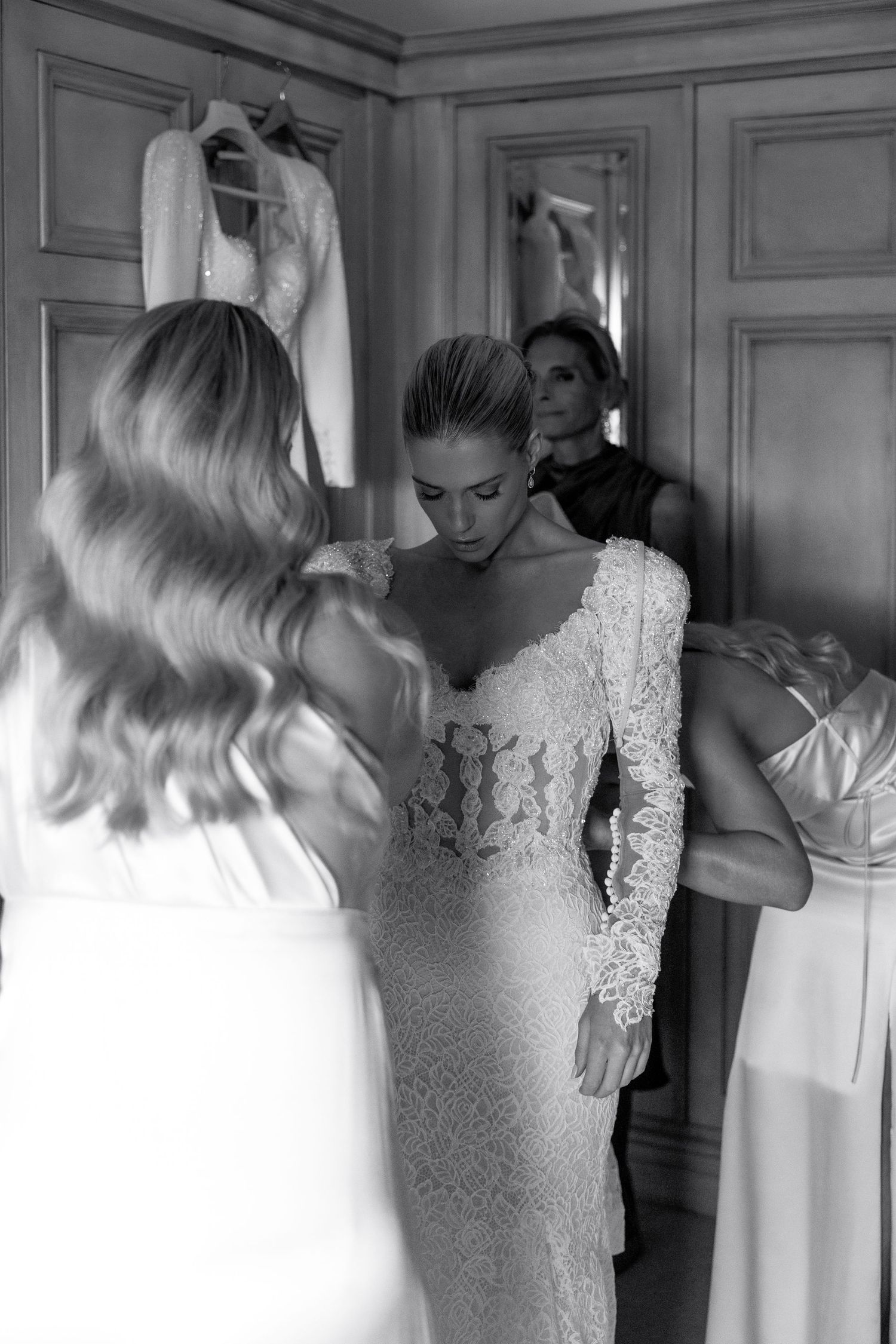 Black and white image showing preparations in an elegant dressing room with white gowns.