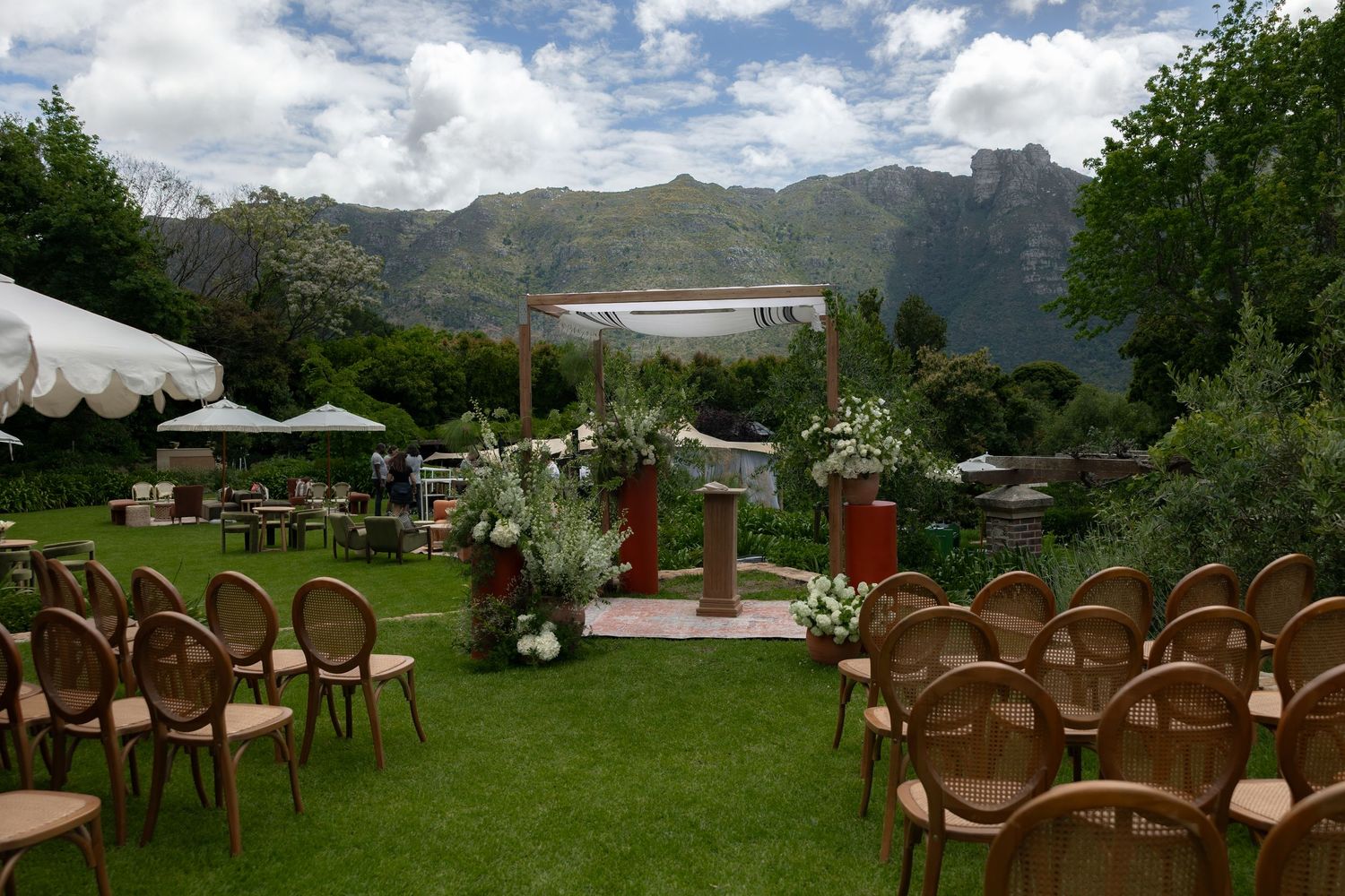 Rows of brown wooden chairs set up for an outdoor wedding ceremony with scenic mountain views and lush greenery.
