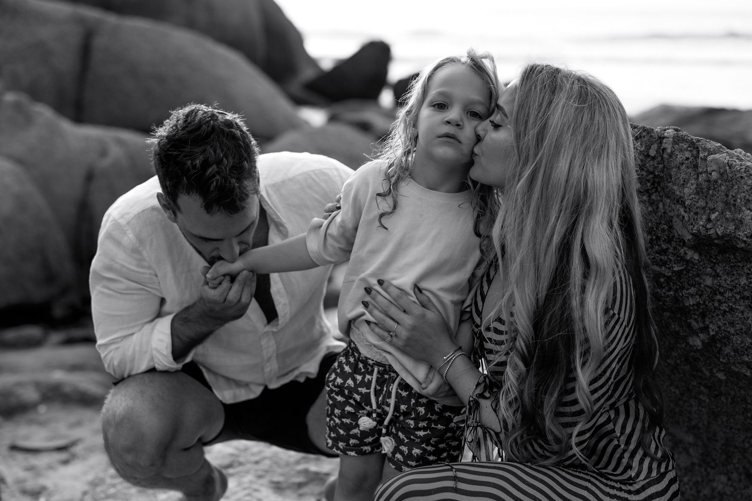Intimate black and white portrait session on rocky coastal beach setting.