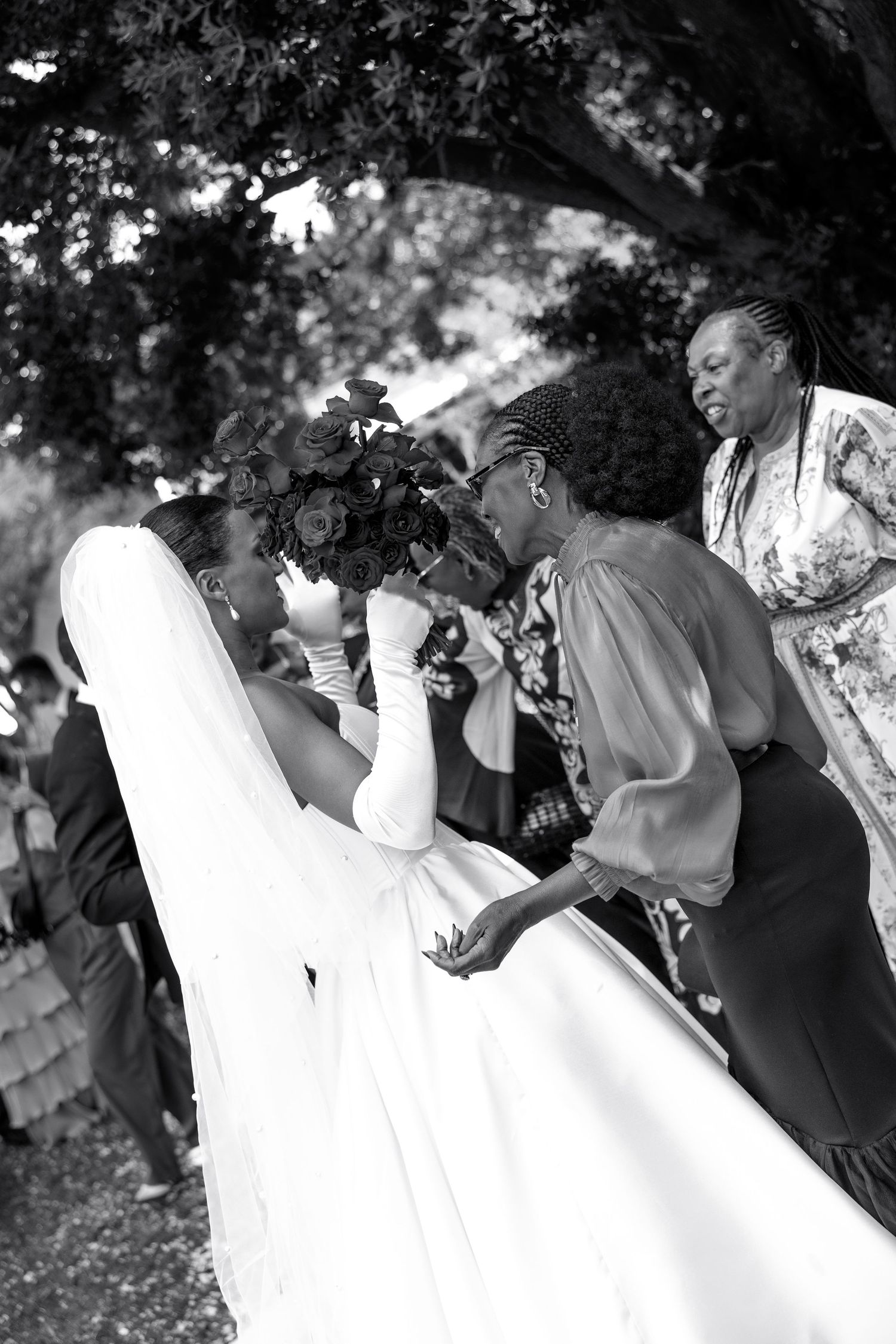 Wedding party dancing and celebrating outdoors with the bride in a flowing white dress.