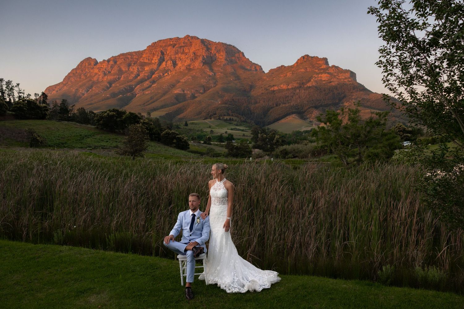A scenic mountain wedding ceremony at sunset with dramatic red-orange peaks in the background.