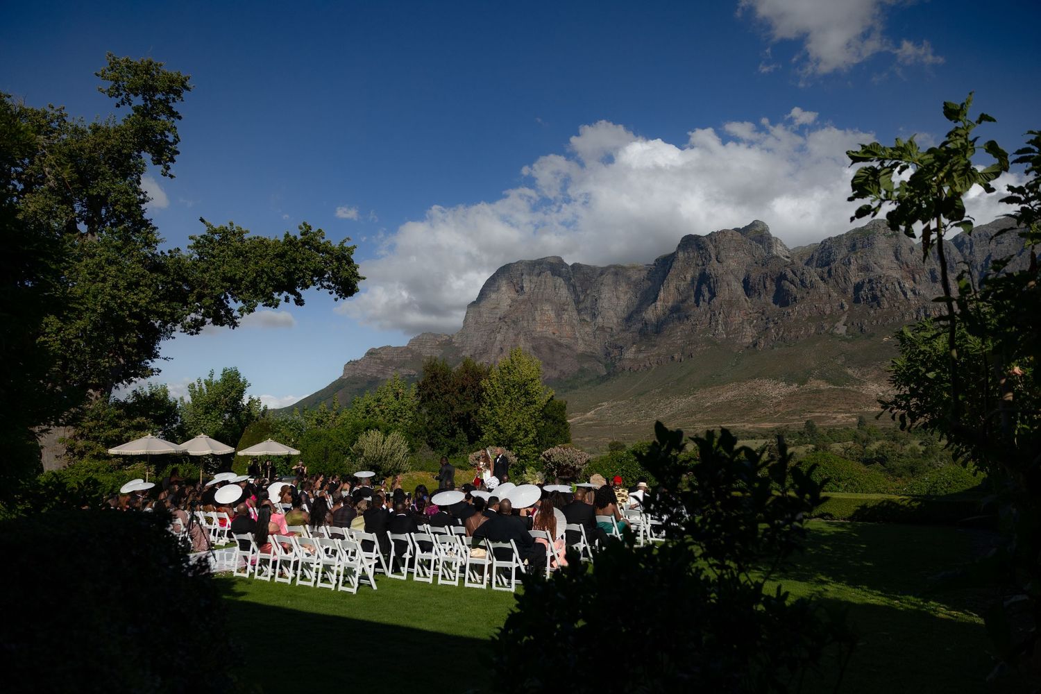 Panoramic view of a wine estate nestled against dramatic mountain peaks in South Africa's Cape Winelands.